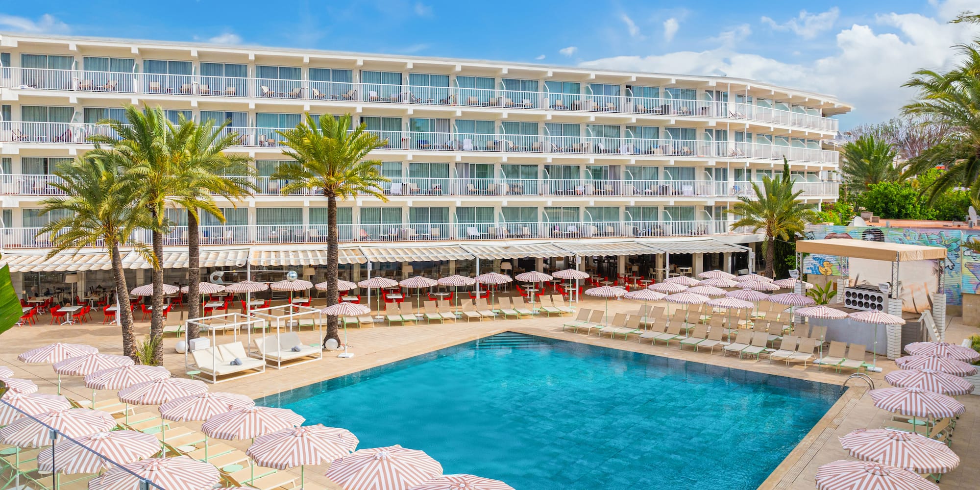 a pool with umbrellas and chairs in front of a hotel
