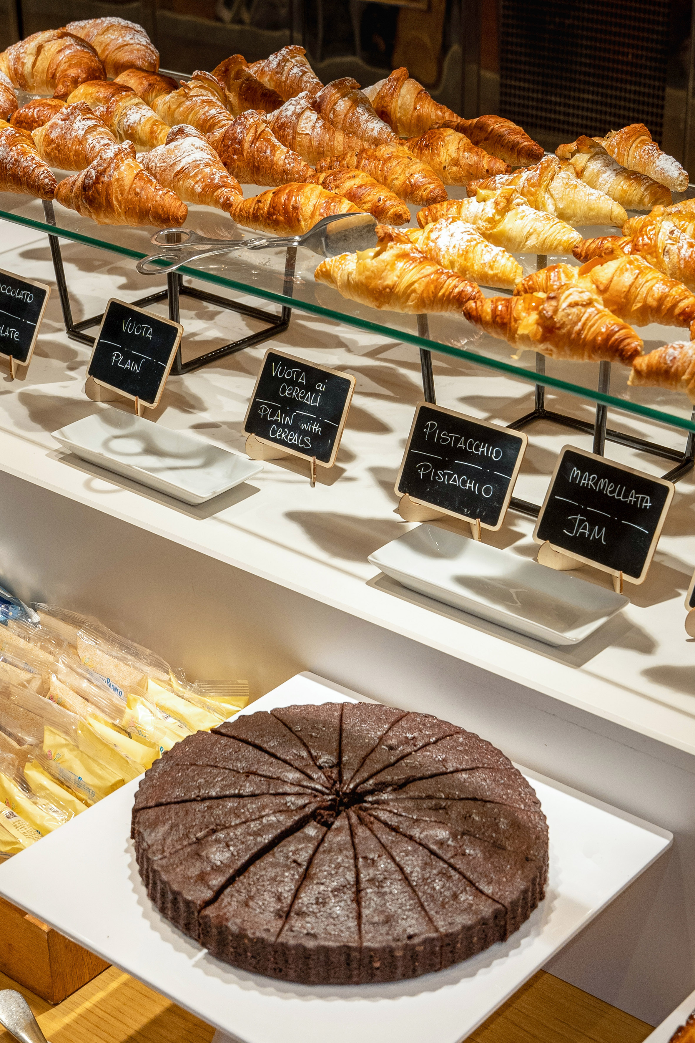 Breakfast buffet with assorted croissants and a sliced chocolate cake.