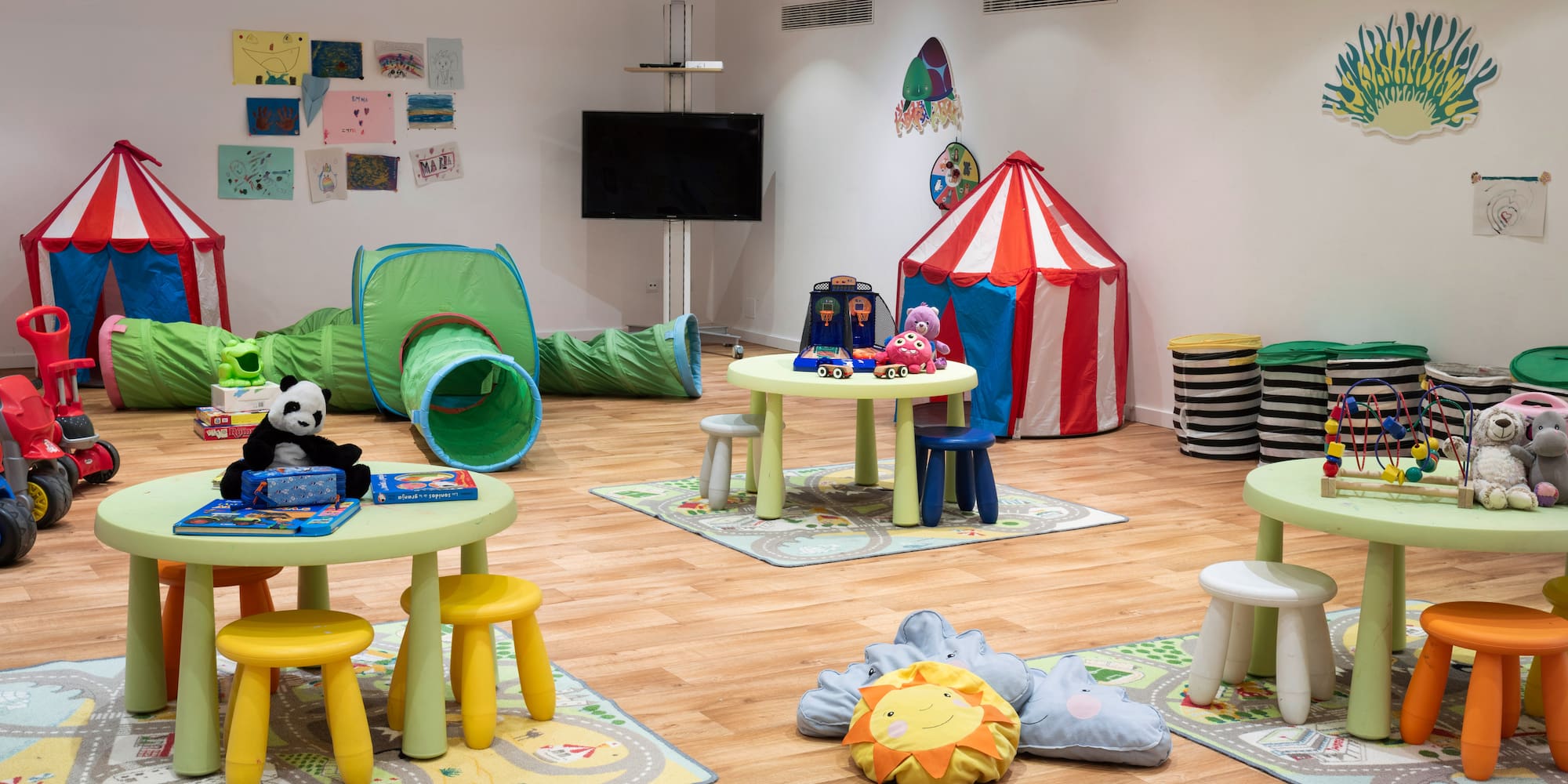 a room with a playroom with tables and toys