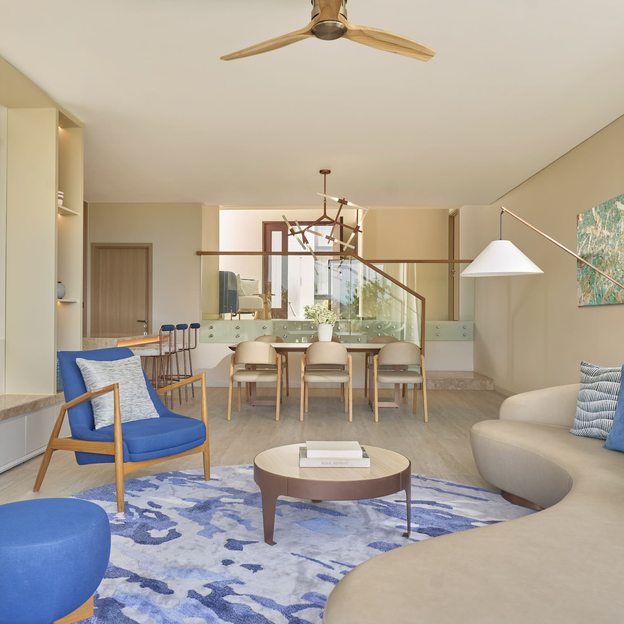 Modern living and dining room with blue accents, beige sofa, and wood details.