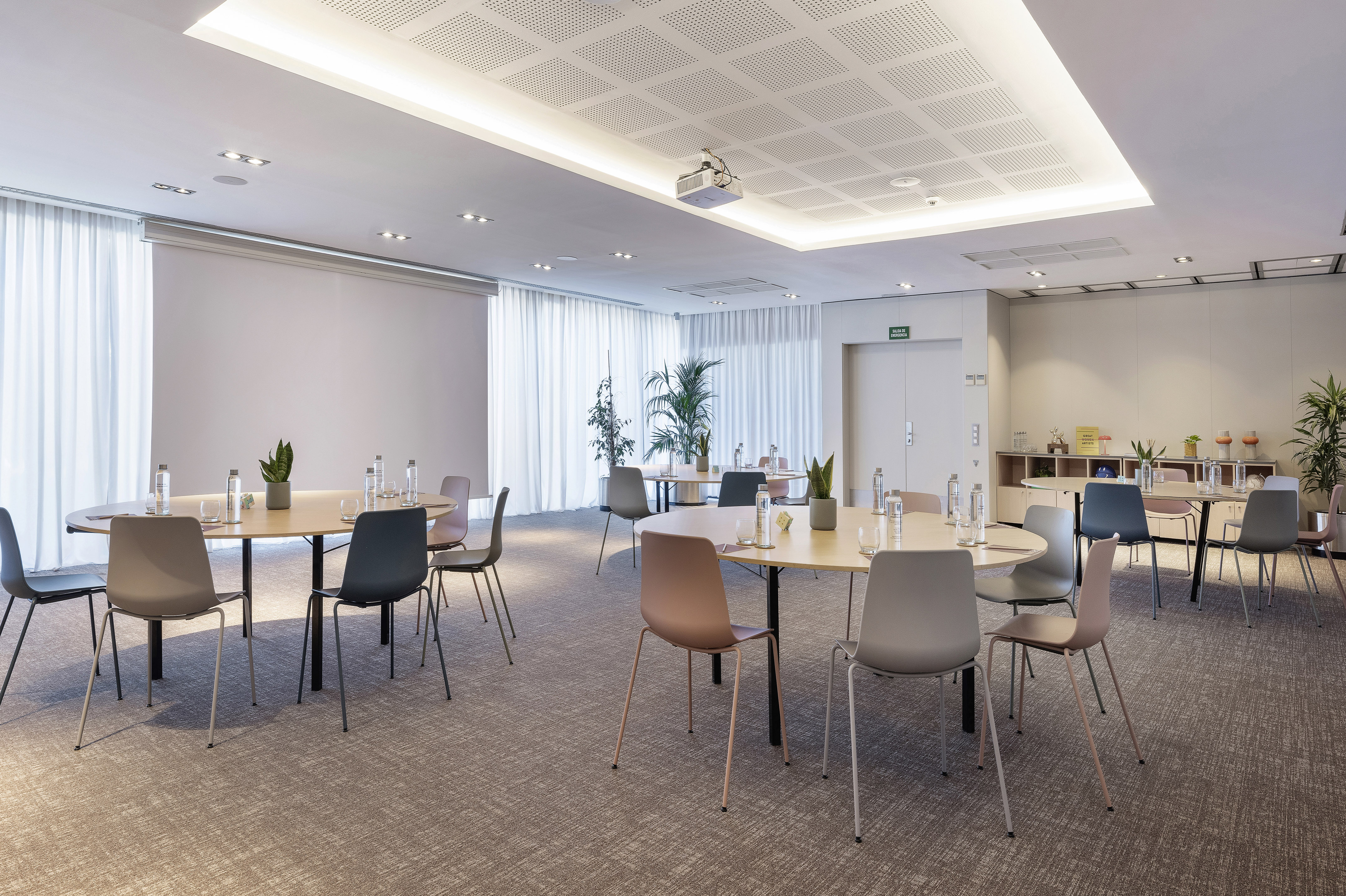 Contemporary meeting room with round tables, modern chairs, and projector.