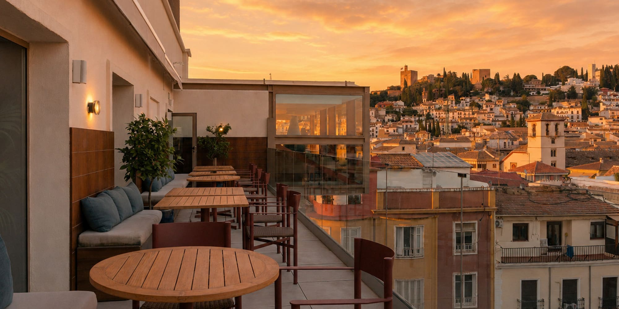 Rooftop terrace dining with sunset views of Granada city and Alhambra.