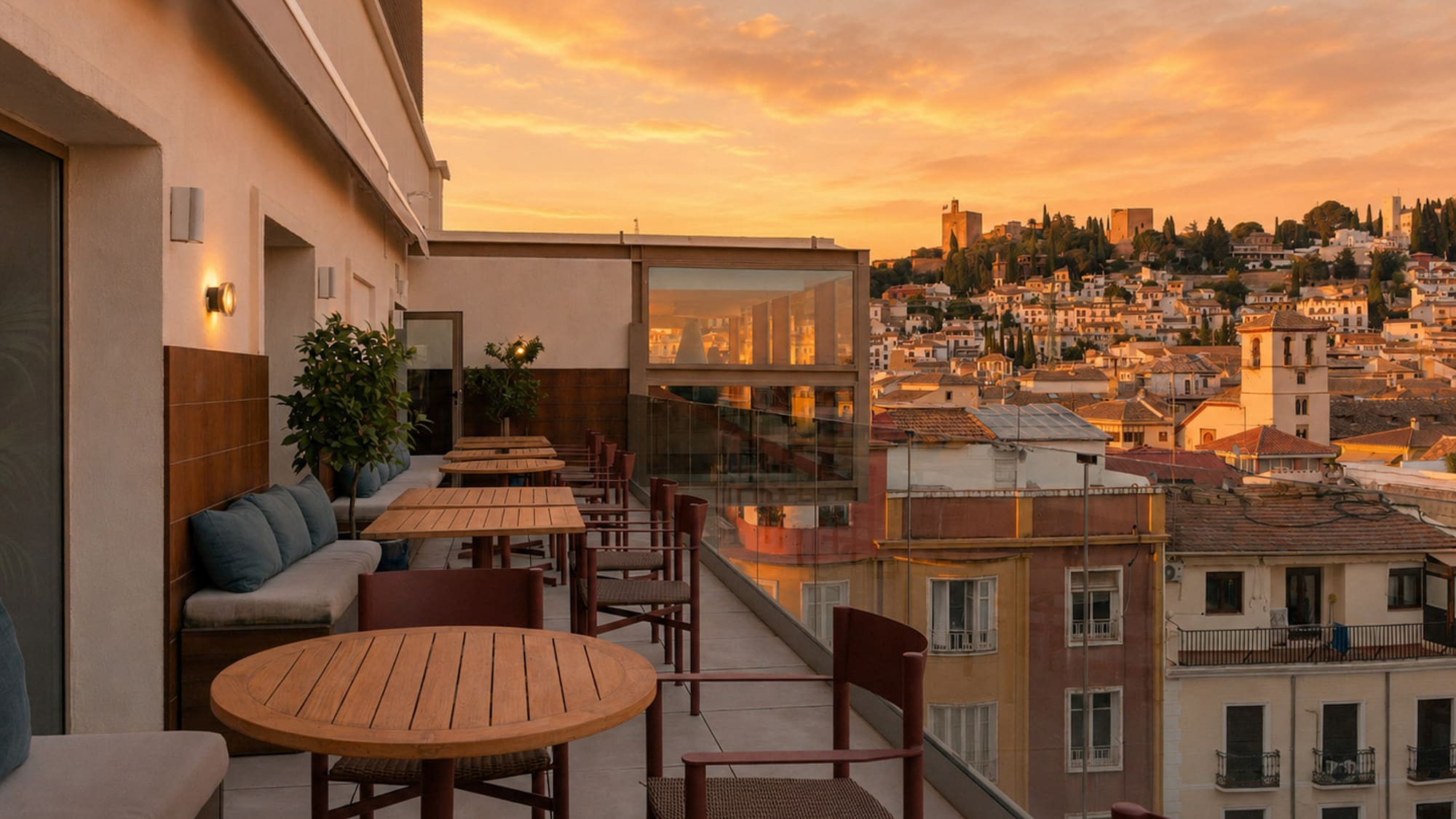 Rooftop terrace dining with sunset views of Granada city and Alhambra.