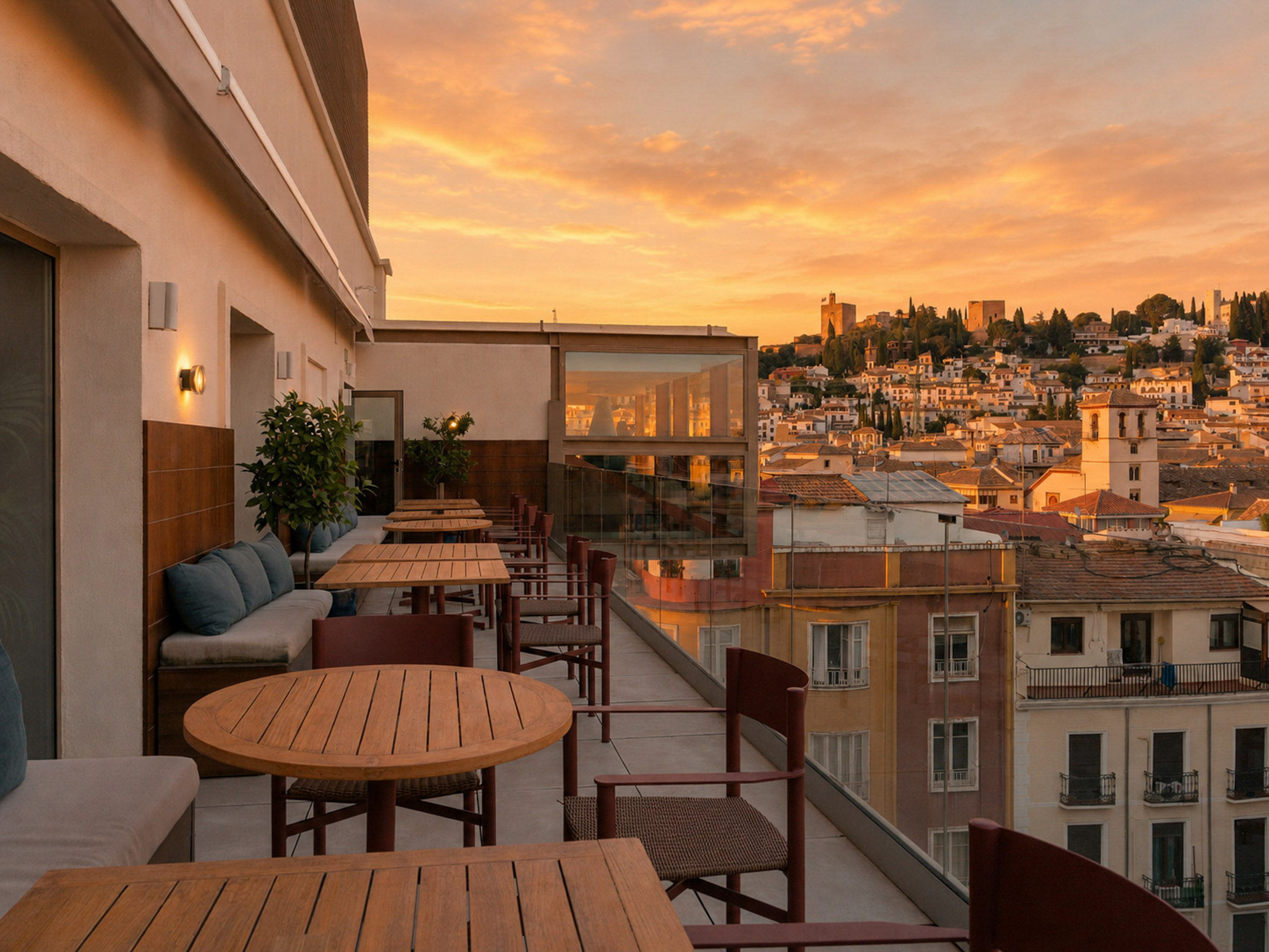 Rooftop terrace dining with sunset views of Granada city and Alhambra.