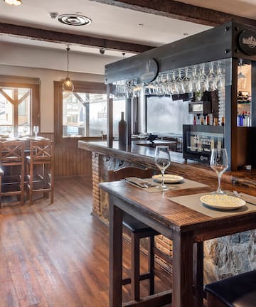 a bar with wine glasses and plates on a wooden table