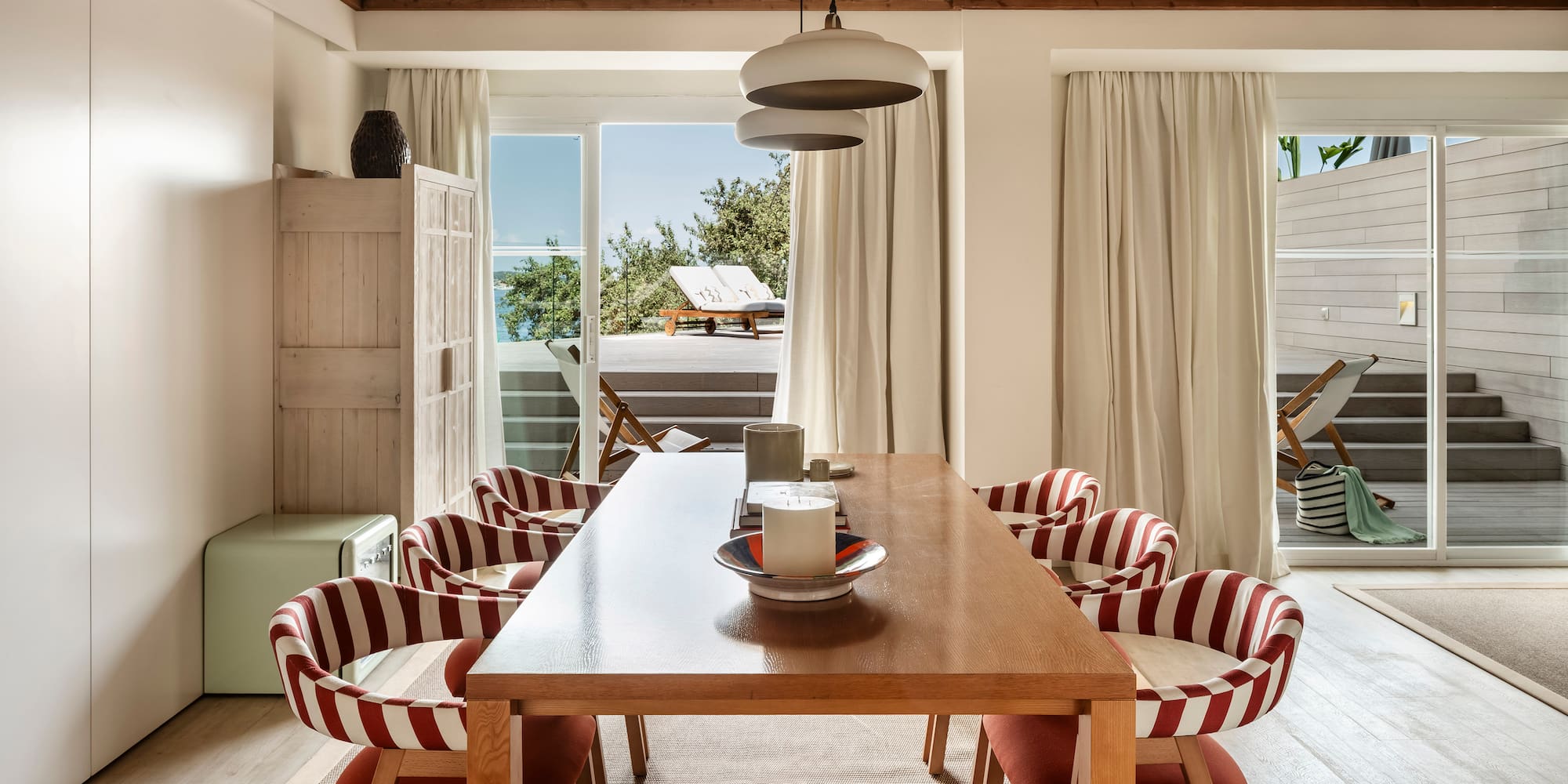 a dining table with chairs in a room with a view of the ocean