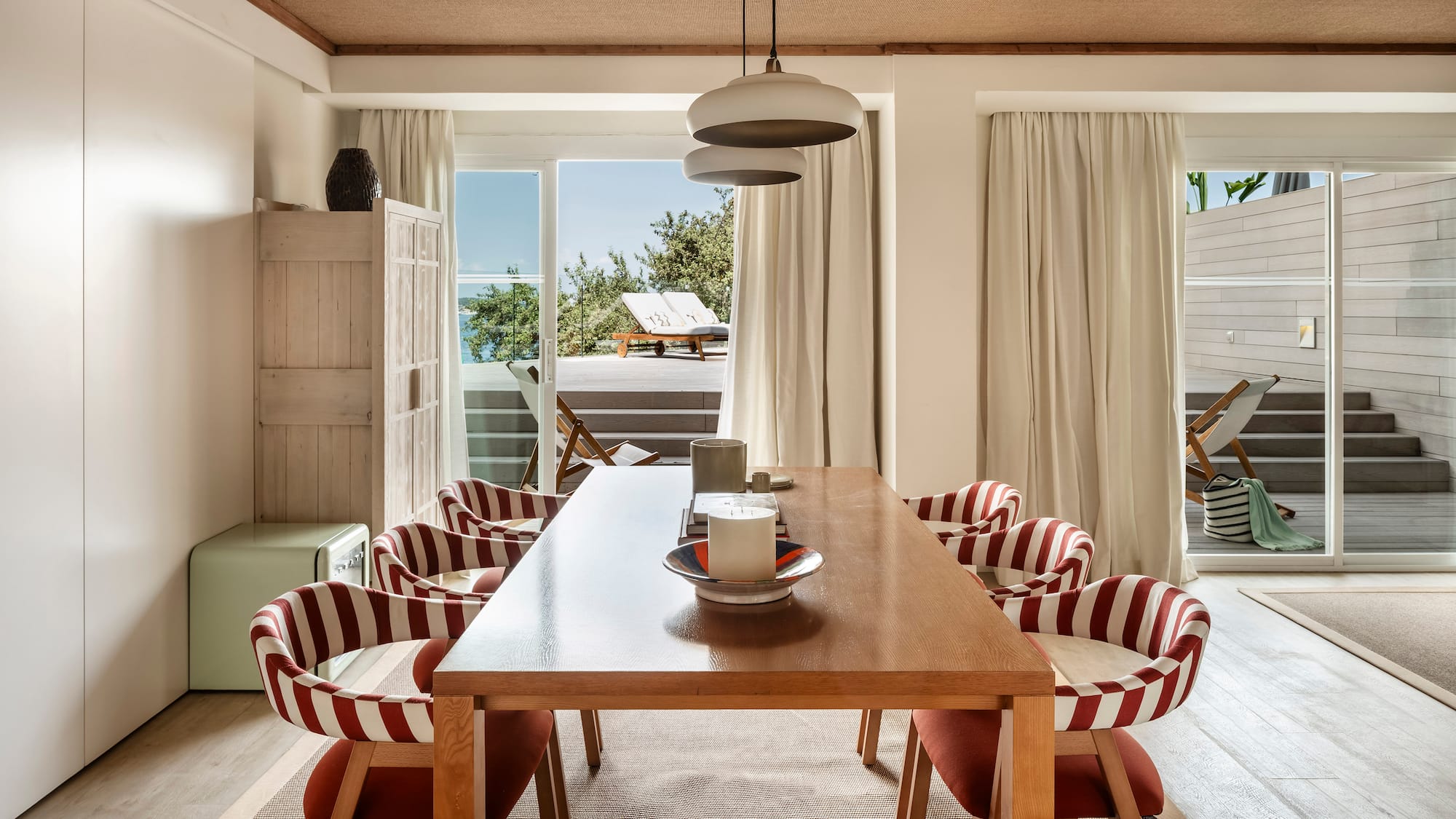 a dining table with chairs in a room with a view of the ocean