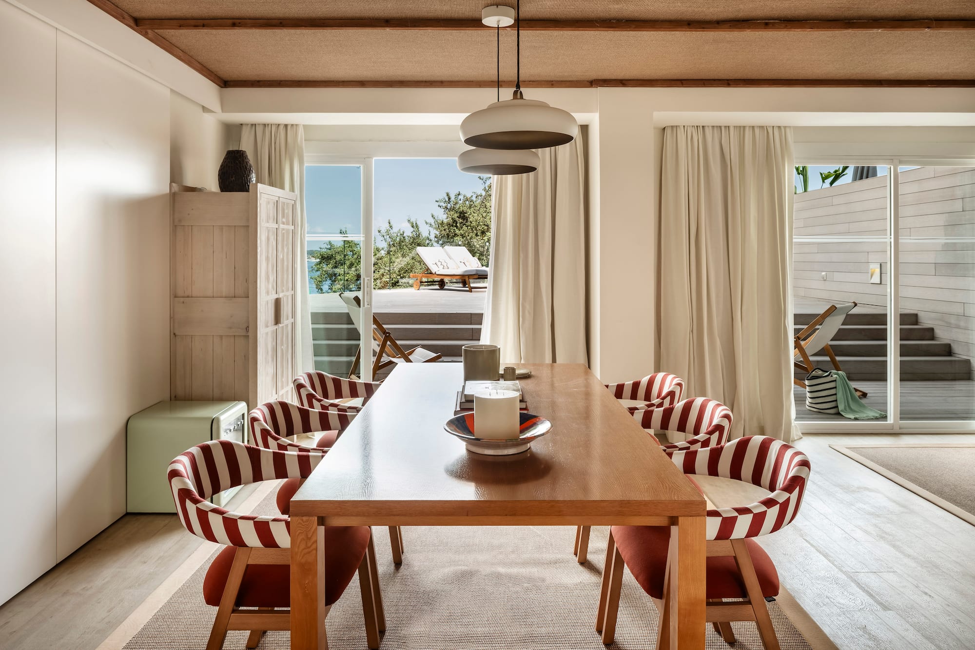 a dining table with chairs in a room with a view of the ocean