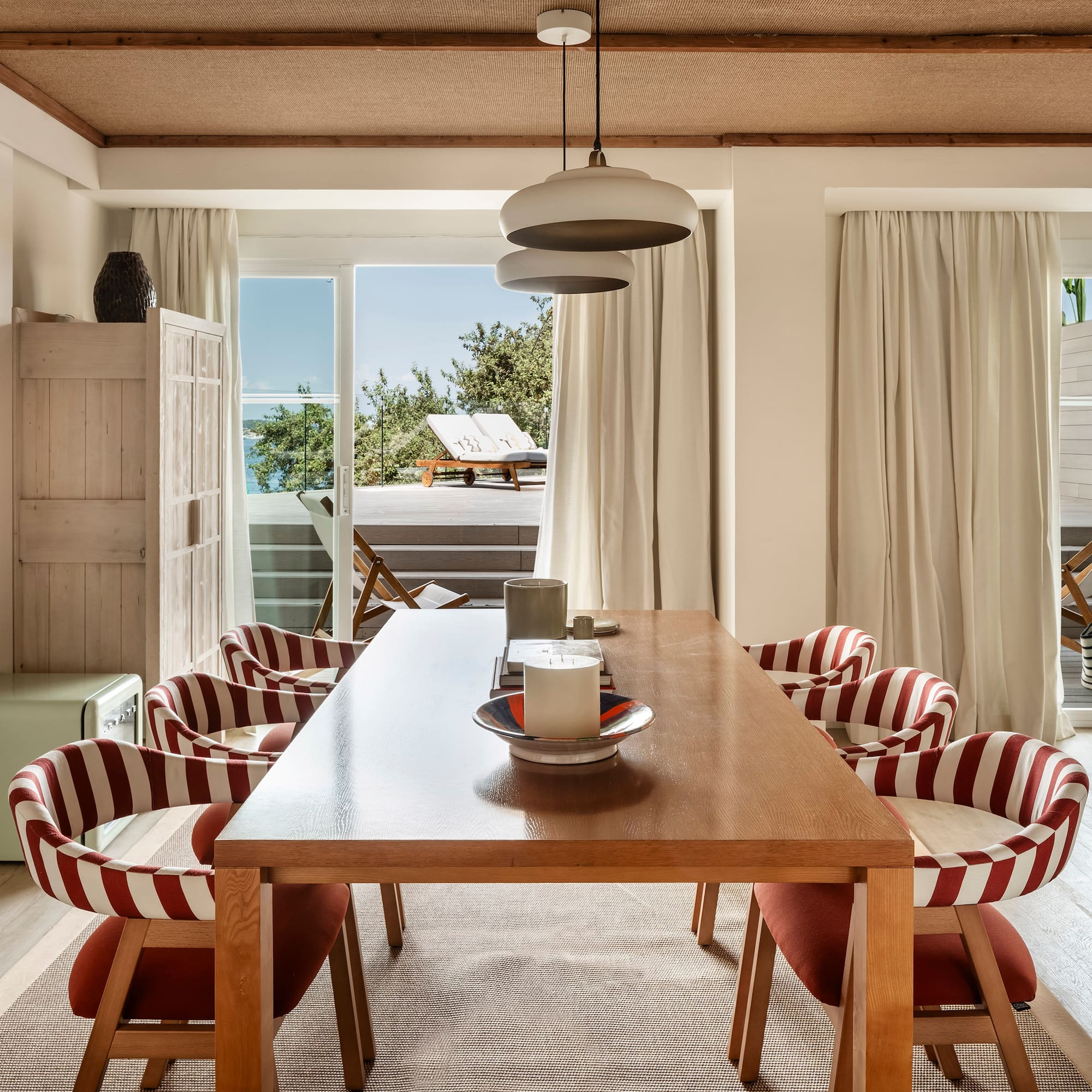 a dining table with chairs in a room with a view of the ocean
