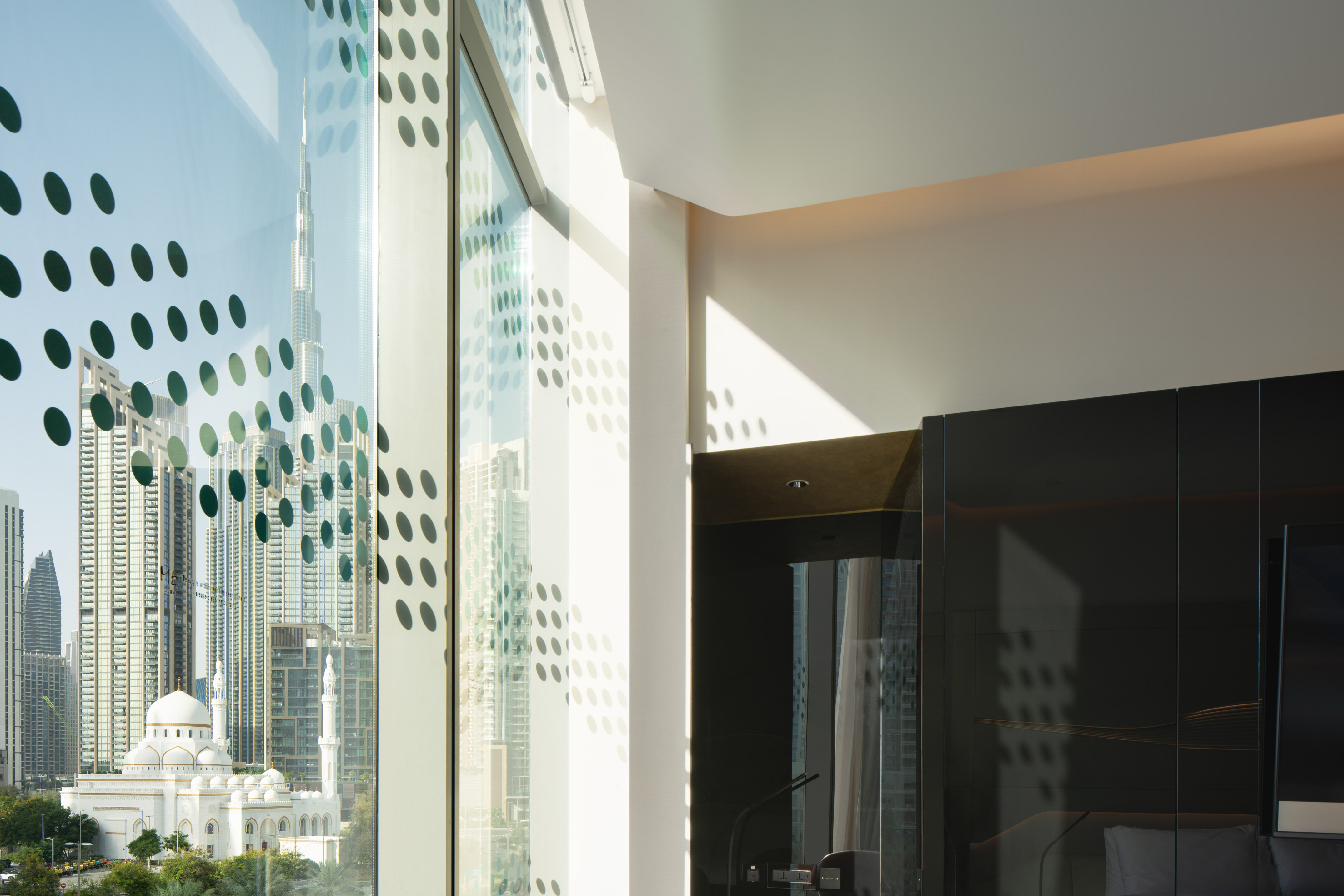 Modern room with patterned window view of Dubai, Burj Khalifa, and a mosque.