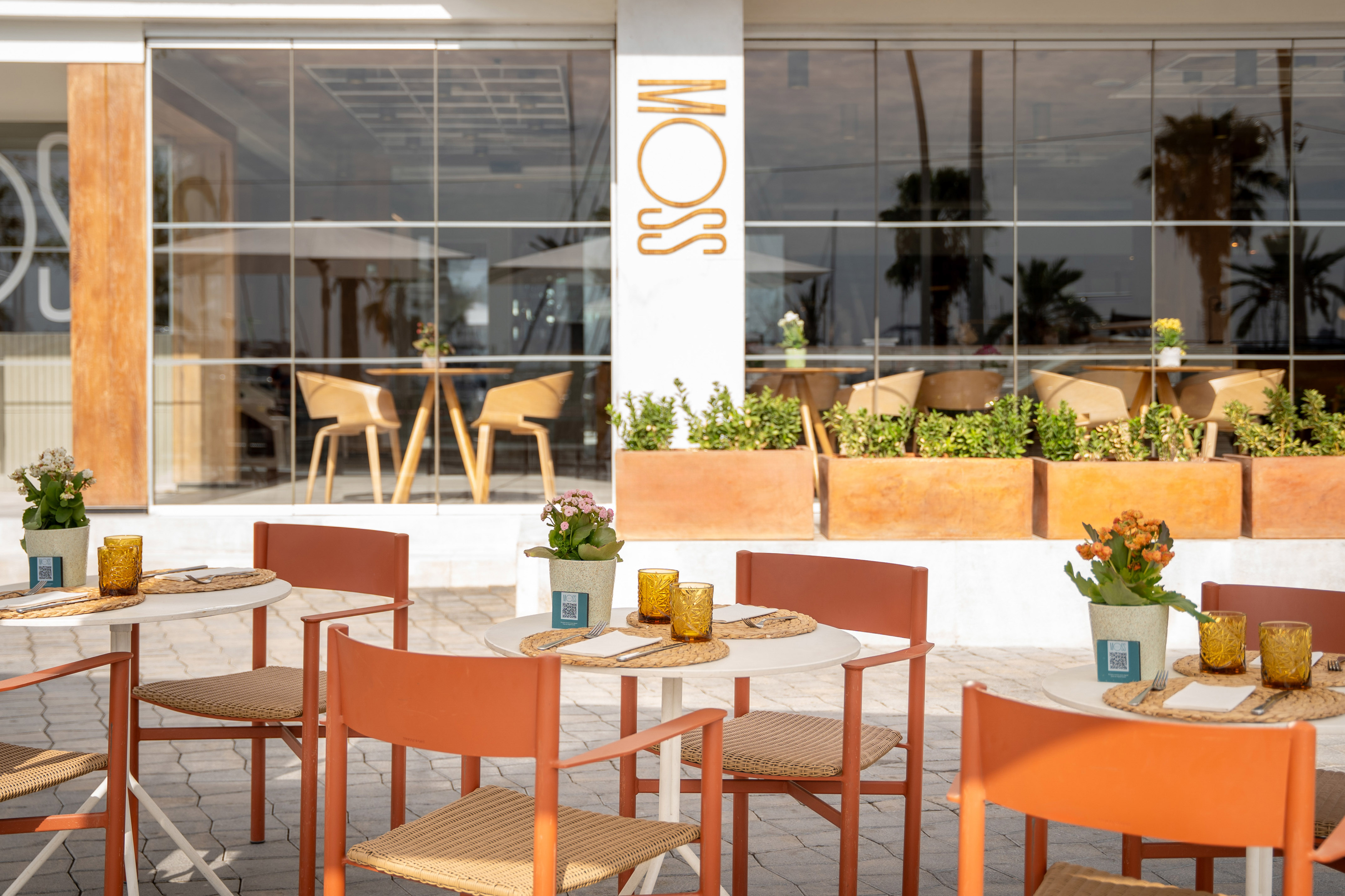 Moss restaurant outdoor seating with modern orange chairs and tables.