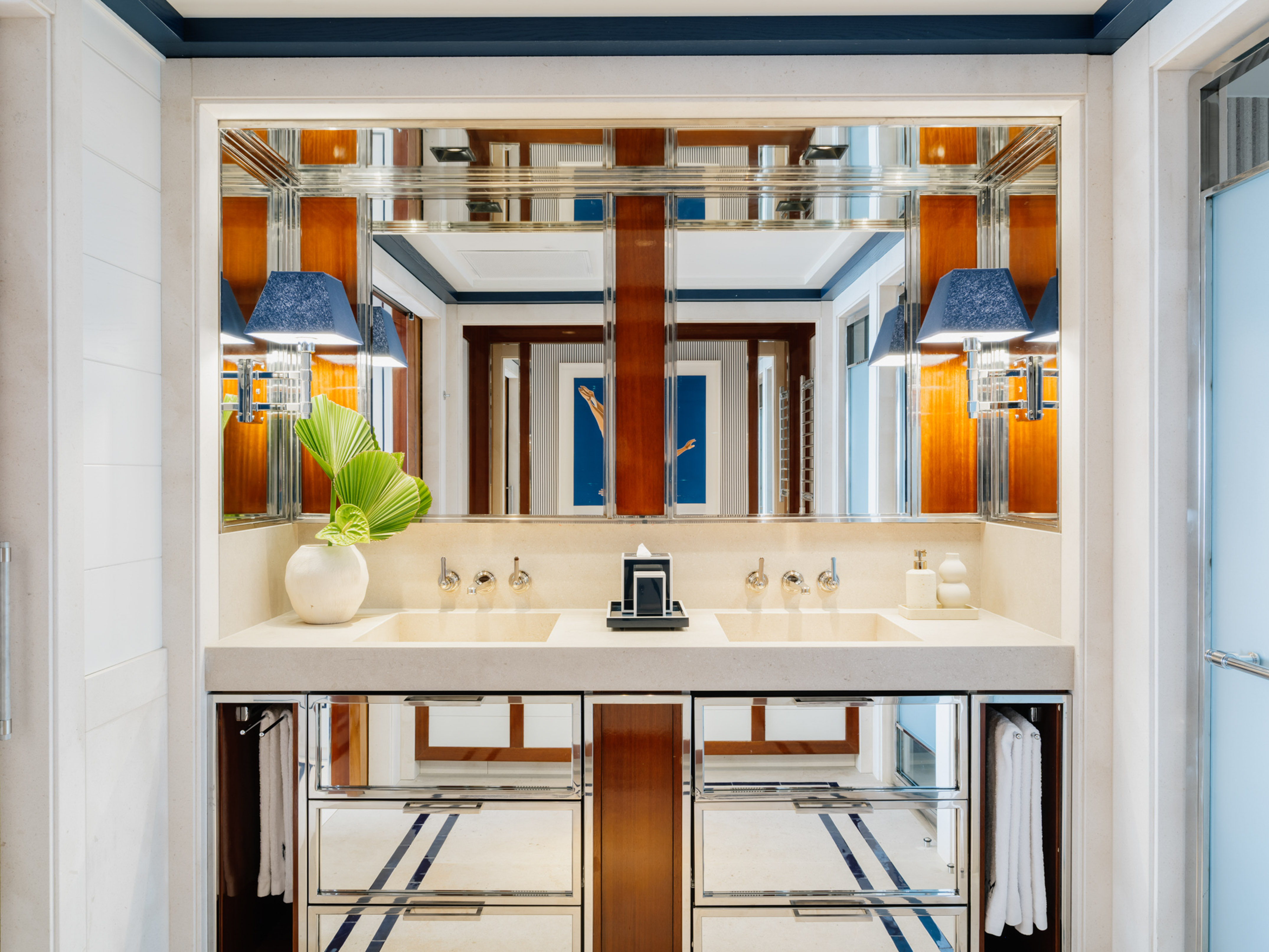 Luxury double vanity bathroom, dual sinks, mirrored cabinetry, blue sconces.