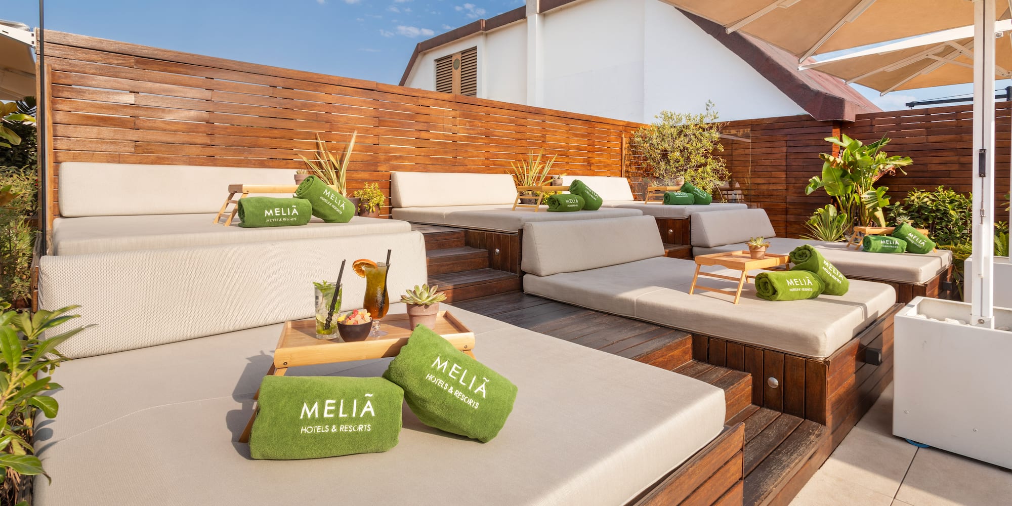 Meliá resort rooftop terrace with lounge daybeds, green towels, and drinks.