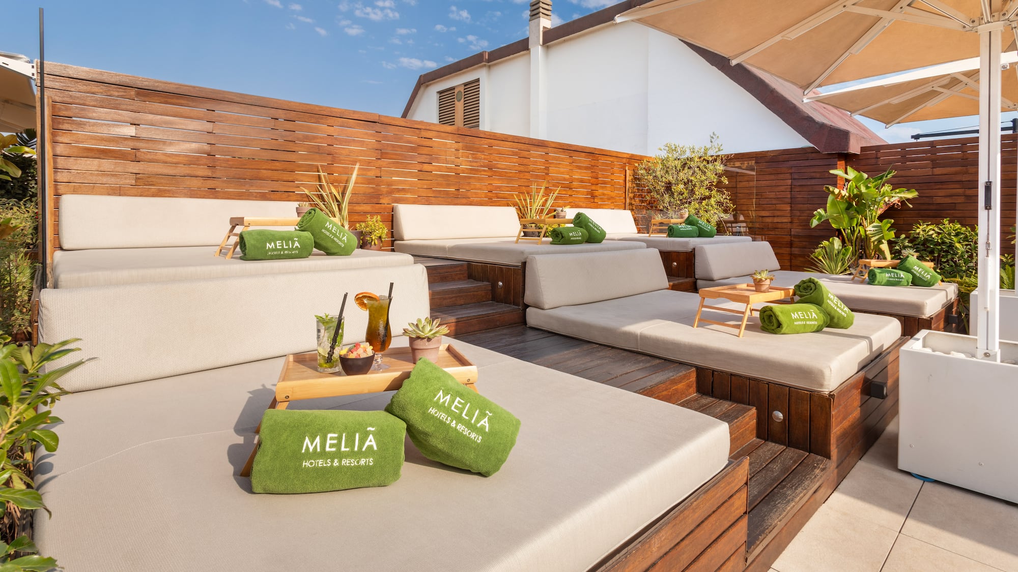Meliá resort rooftop terrace with lounge daybeds, green towels, and drinks.