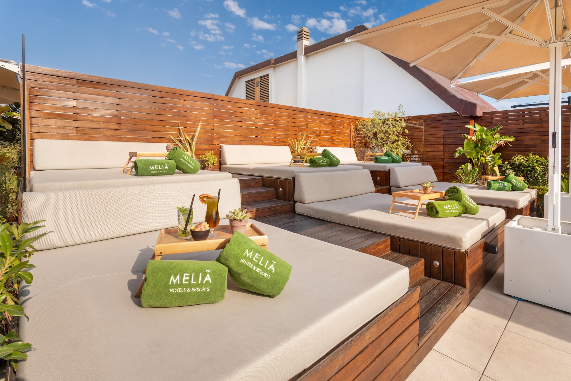 Meliá resort rooftop terrace with lounge daybeds, green towels, and drinks.