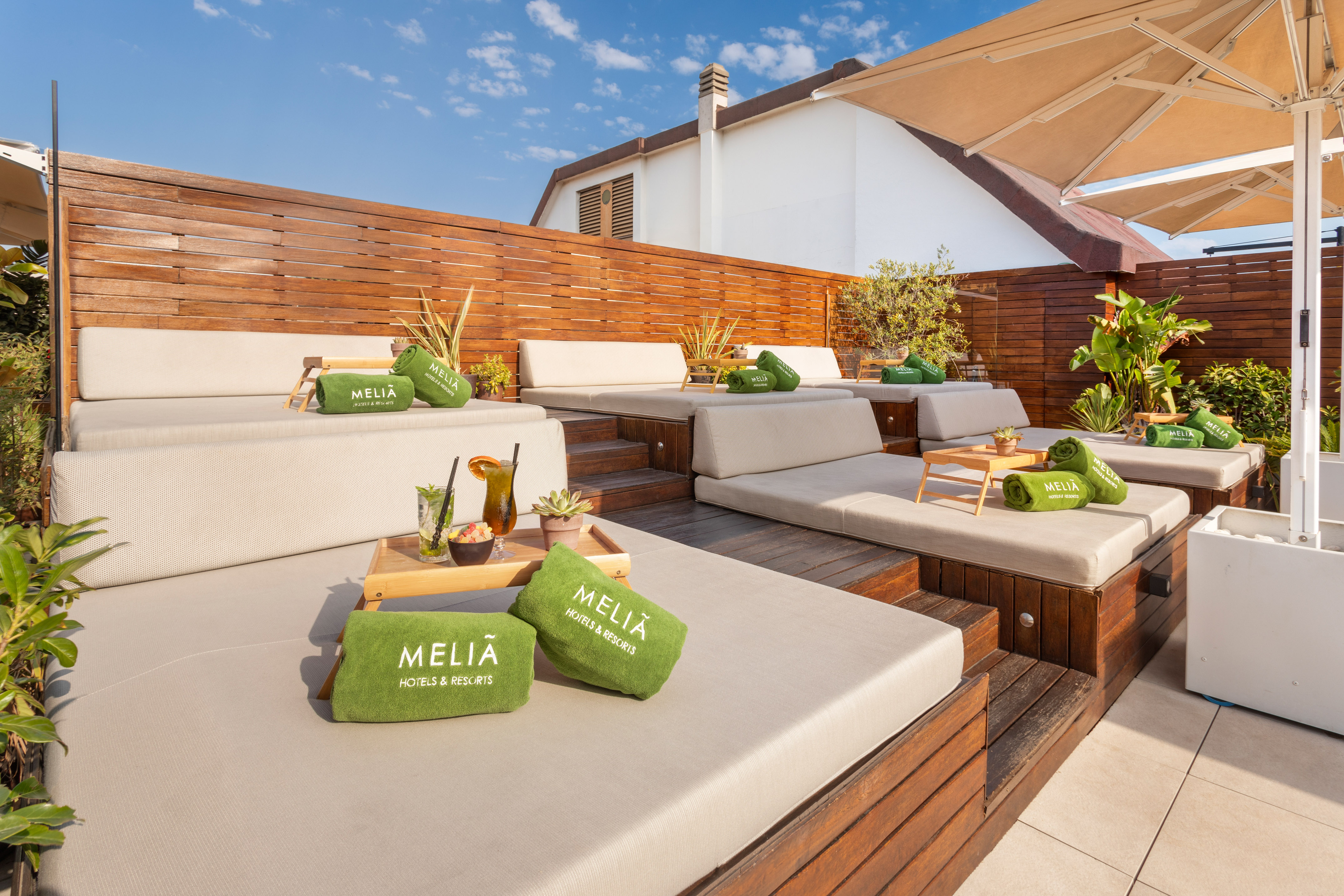 Meliá resort rooftop terrace with lounge daybeds, green towels, and drinks.