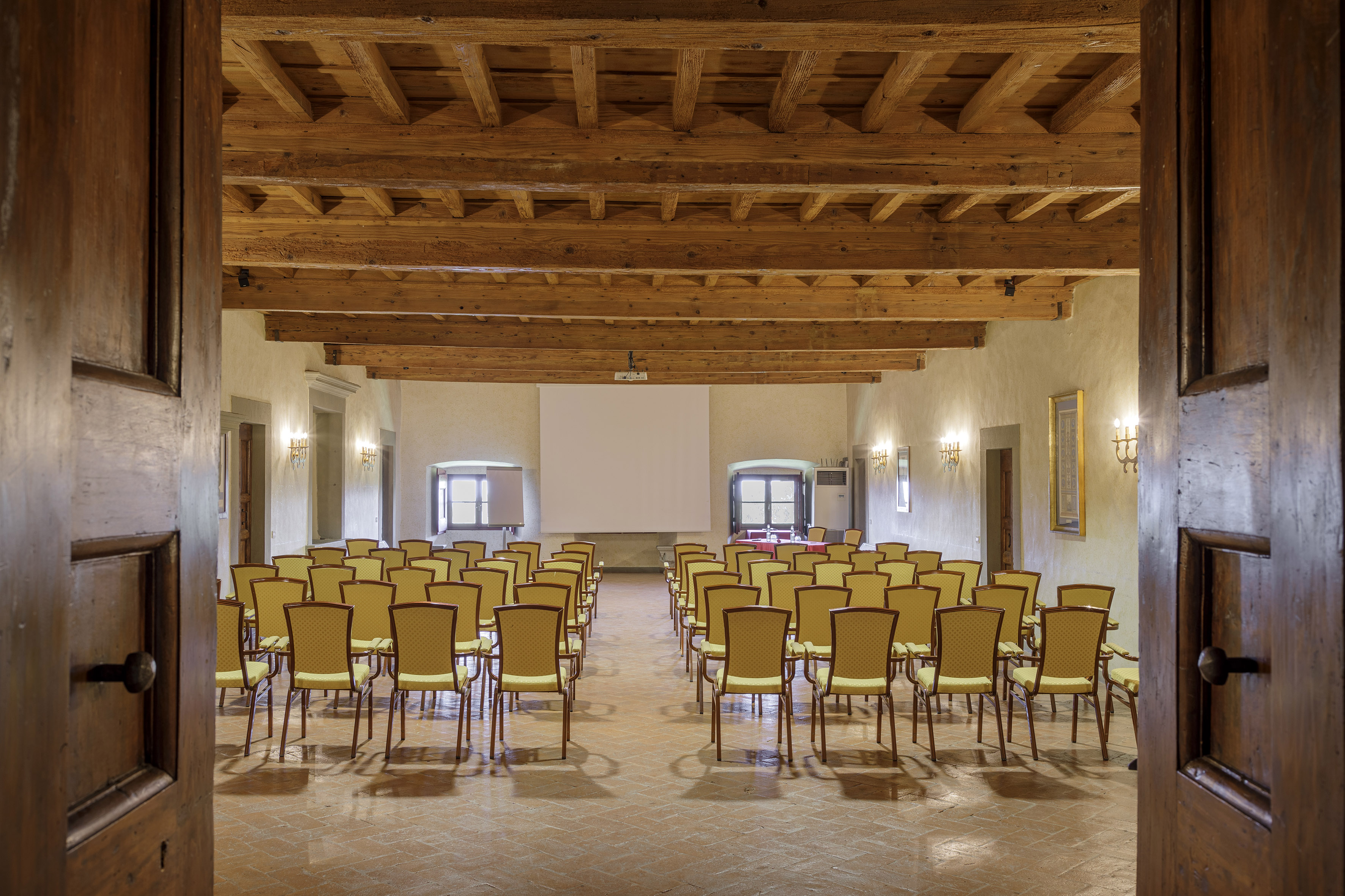 Conference room with yellow chairs, exposed wooden beams, and projector screen.