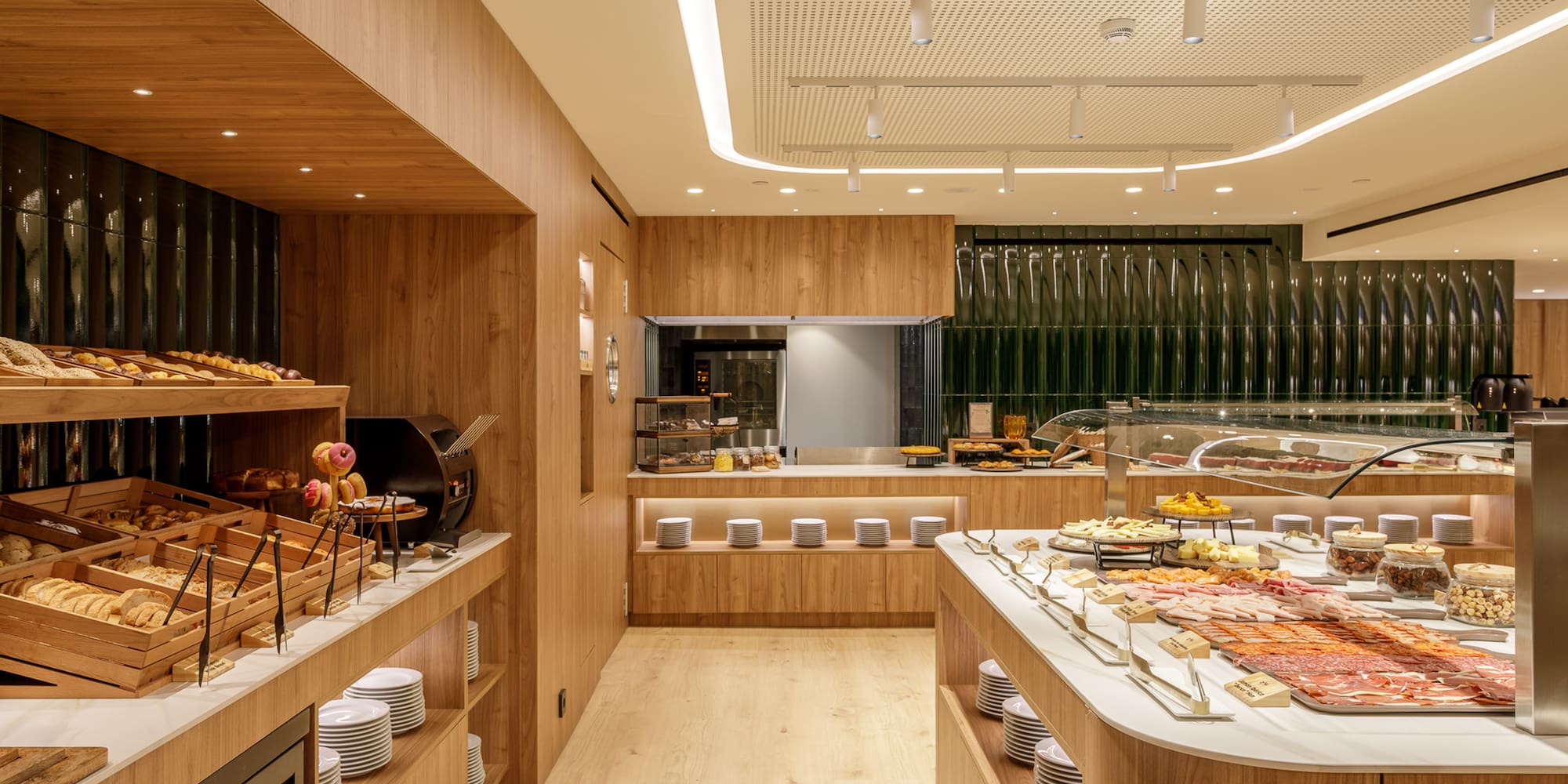 Hotel buffet with fresh bakery, cold cuts, cheeses, and modern wood design.