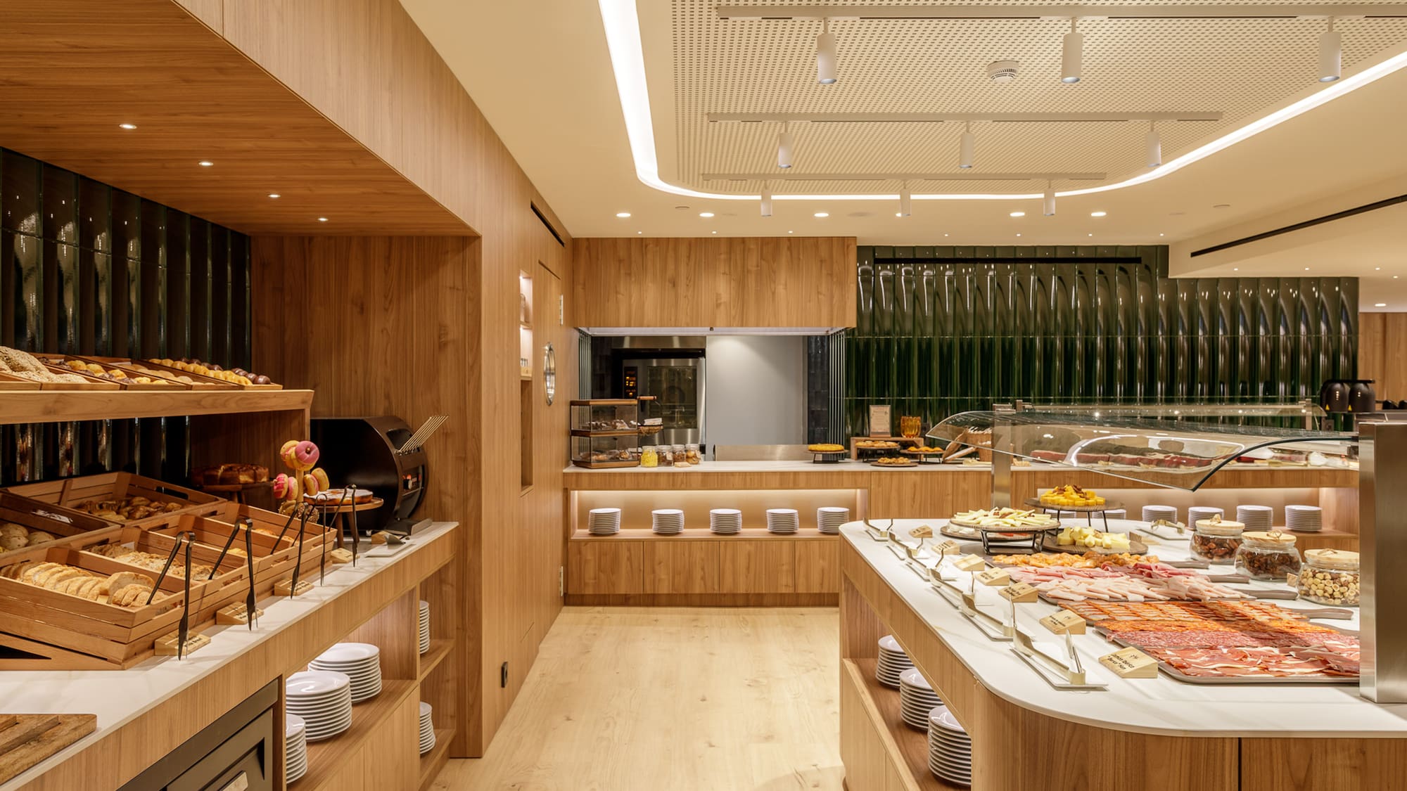 Hotel buffet with fresh bakery, cold cuts, cheeses, and modern wood design.
