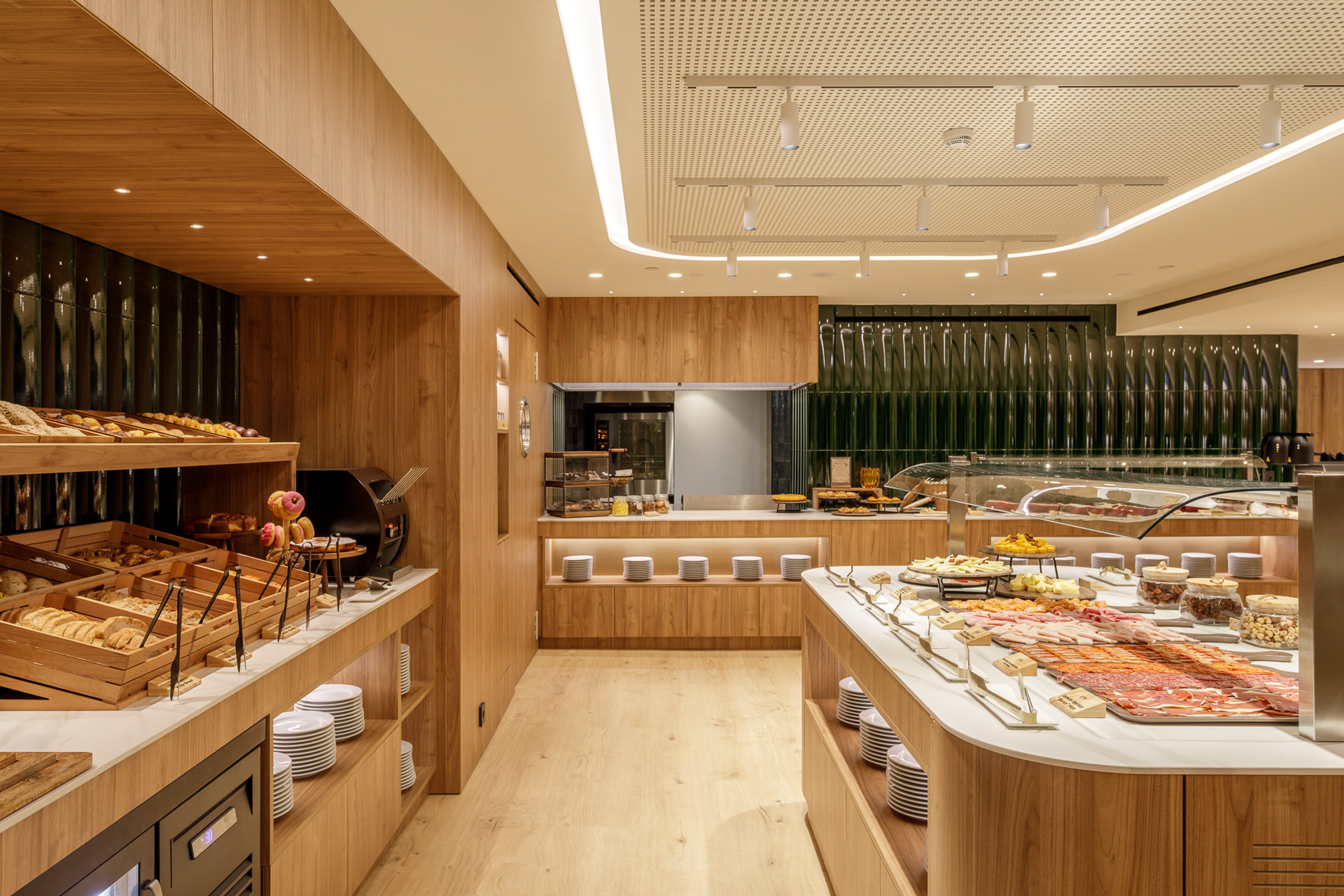 Hotel buffet with fresh bakery, cold cuts, cheeses, and modern wood design.