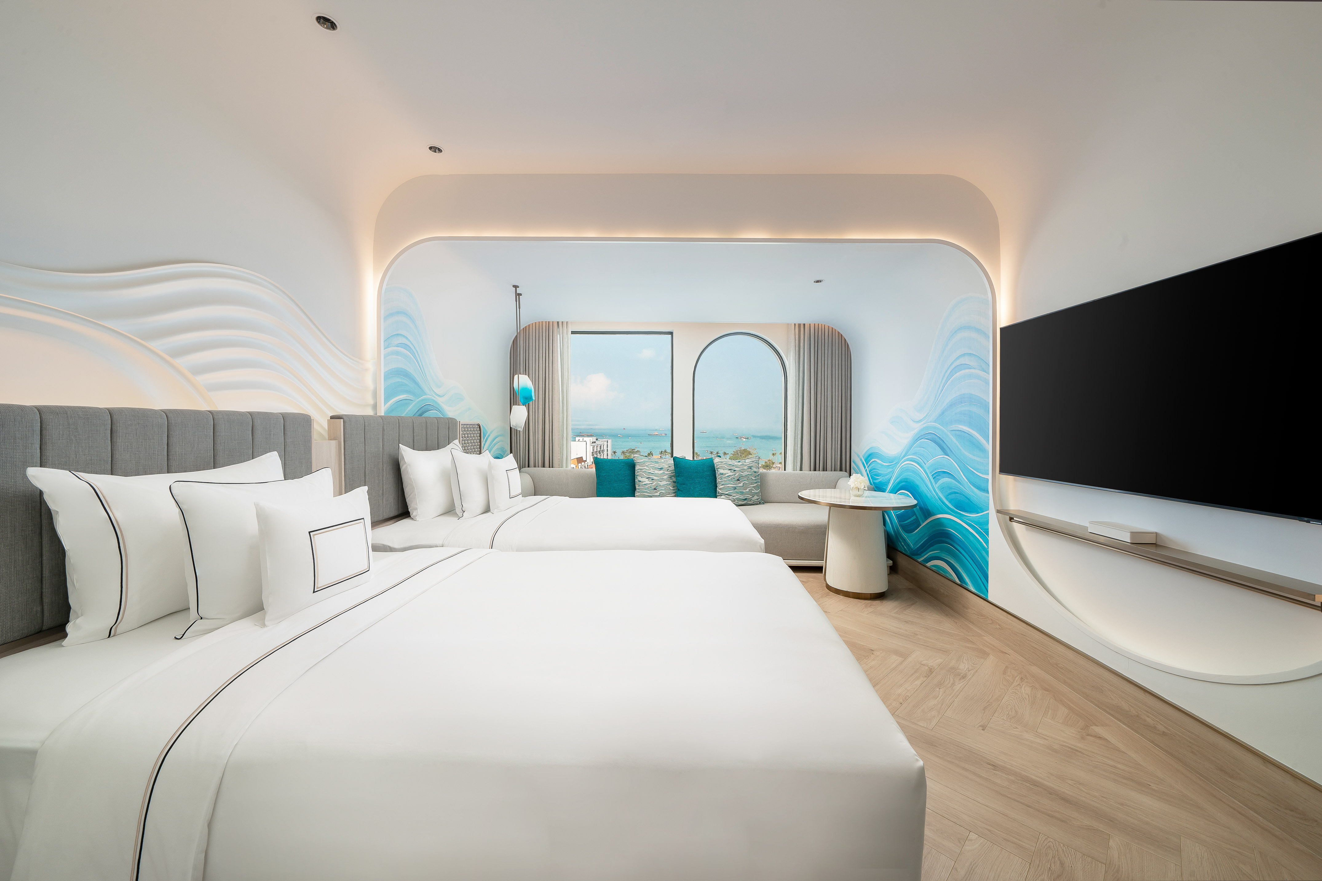 Luxury hotel room with two beds, ocean view, wave mural, and modern design.