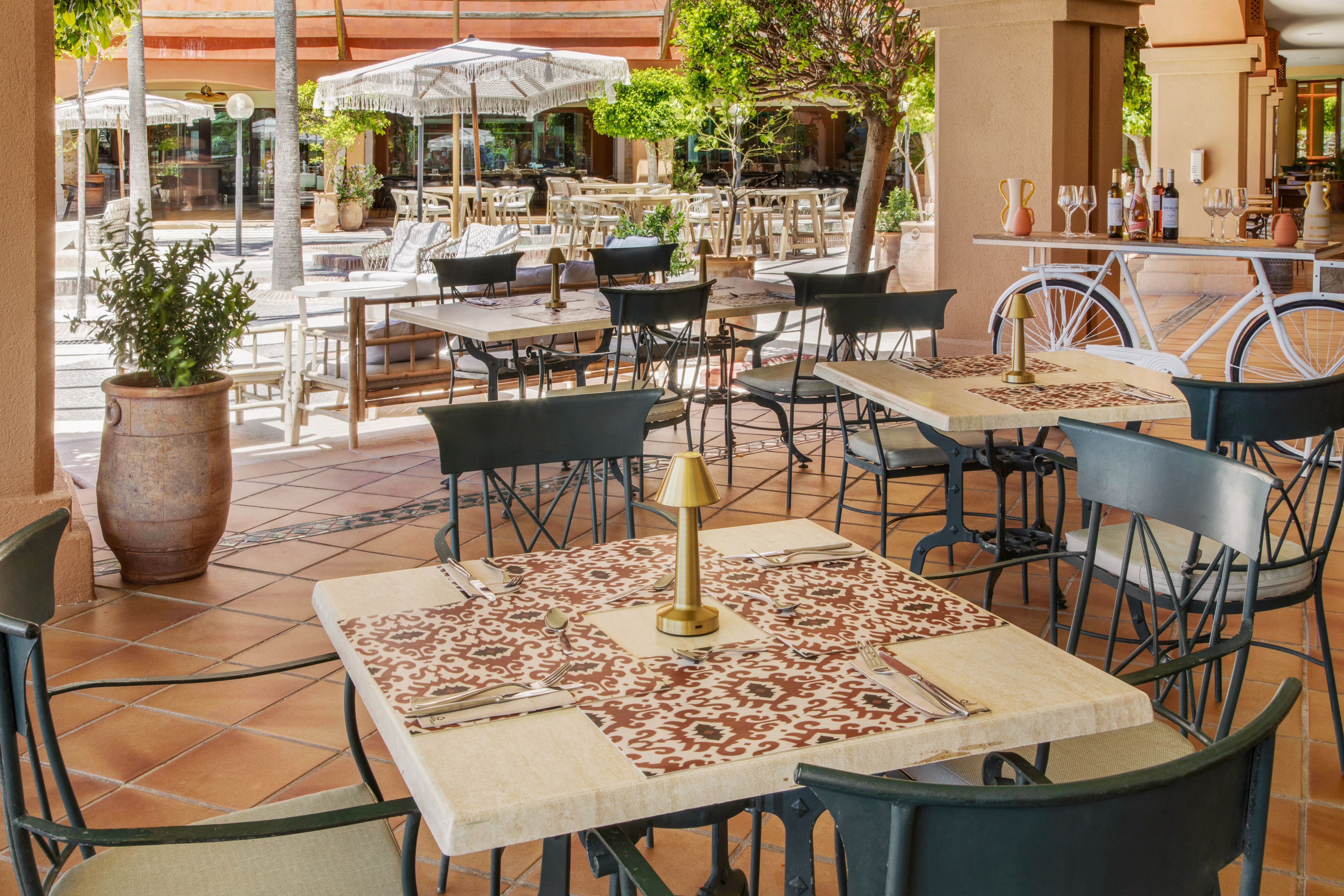 Mediterranean outdoor dining terrace with set tables, chairs, and bicycle decor.