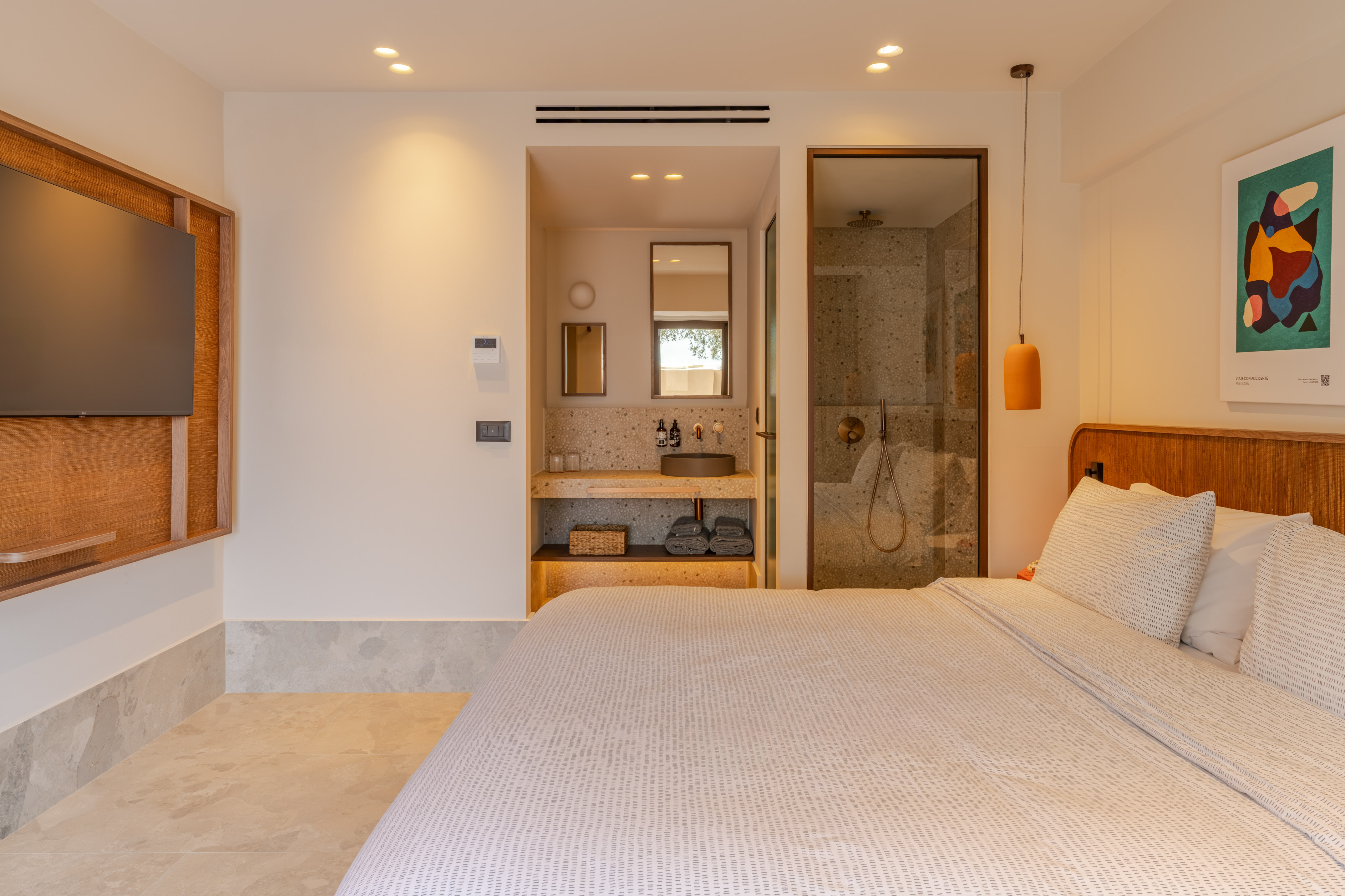 Modern hotel suite with open concept bathroom, vanity, and walk-in shower.