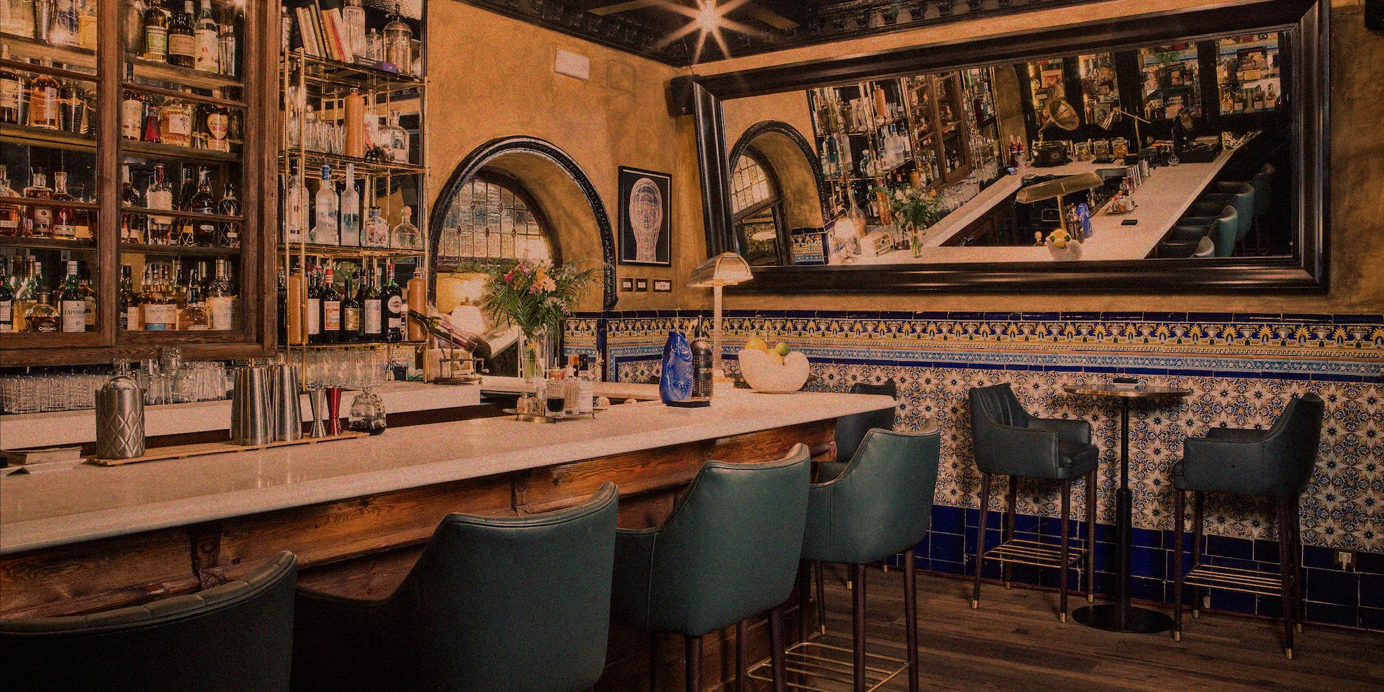 a bar with chairs and a mirror above it