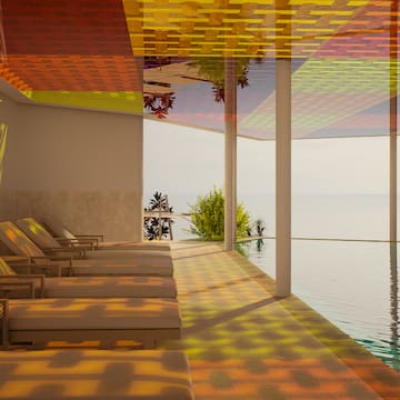 a pool with chairs and a view of the ocean