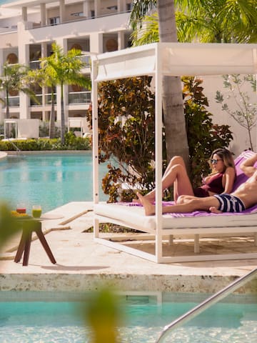 a man and woman lying on a lounge chair by a pool