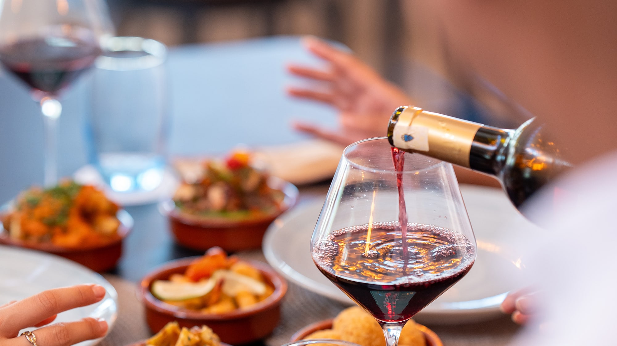 a person pouring wine into a glass of wine