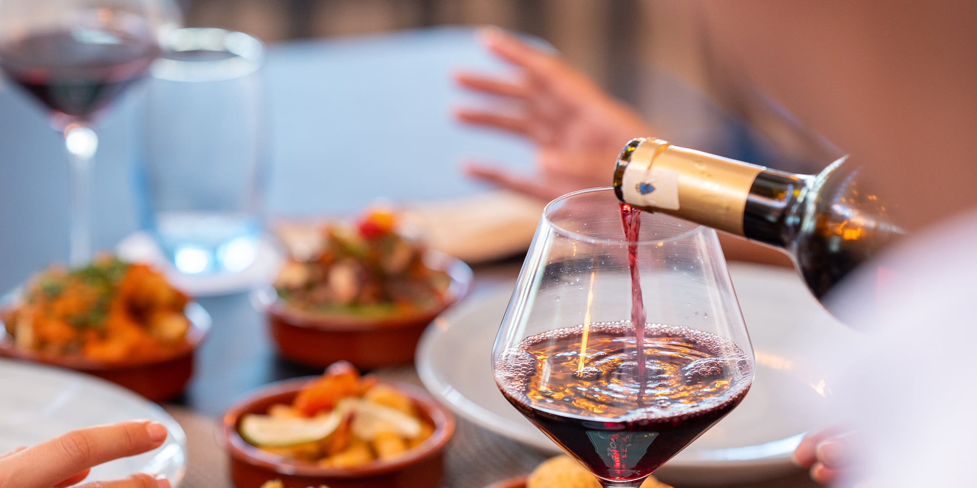 a person pouring wine into a glass of wine