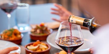 a person pouring wine into a glass of wine