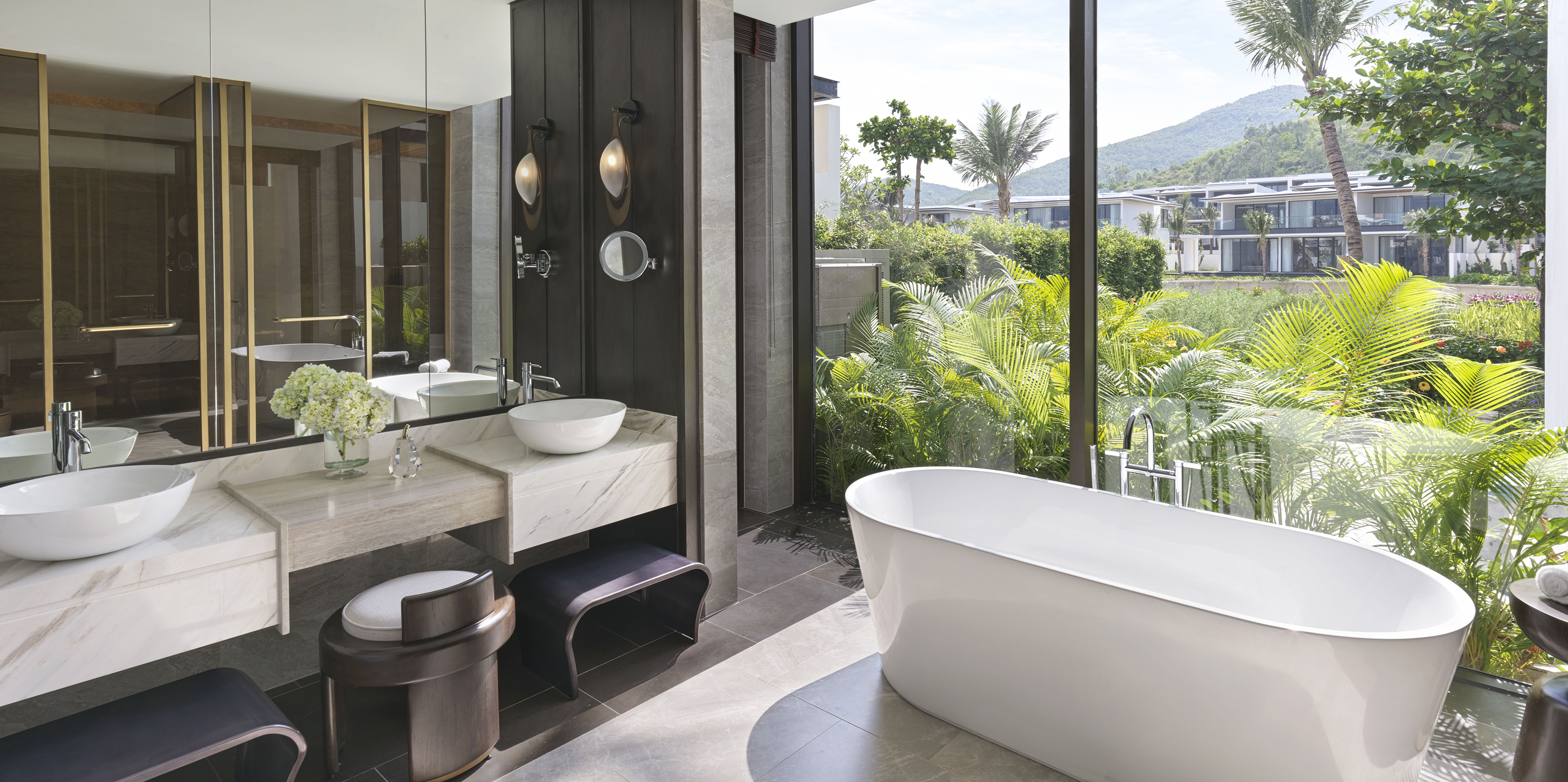 Luxury bathroom with freestanding tub, double vanity, and tropical garden view.
