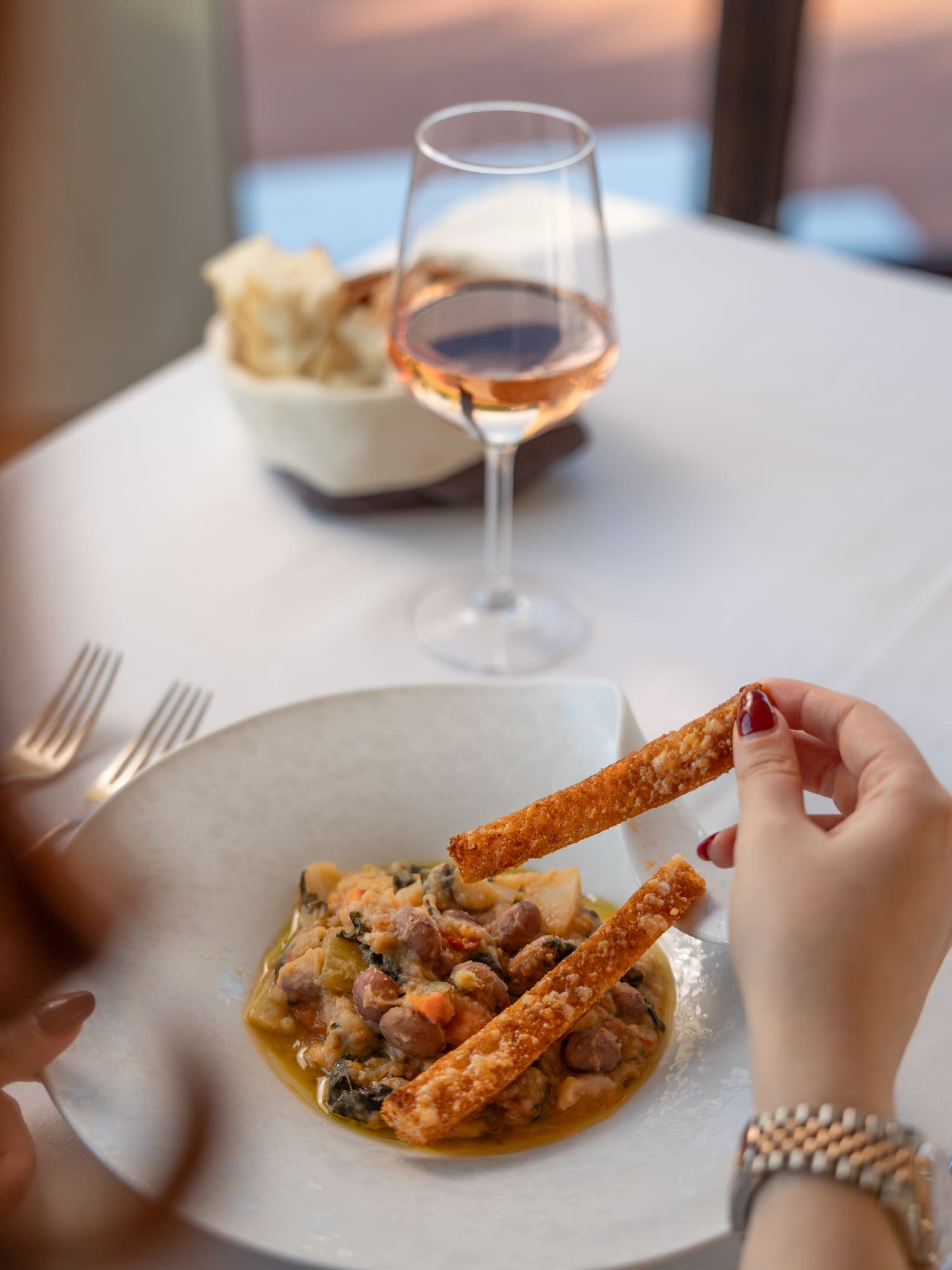 a person holding bread sticks over a plate of food
