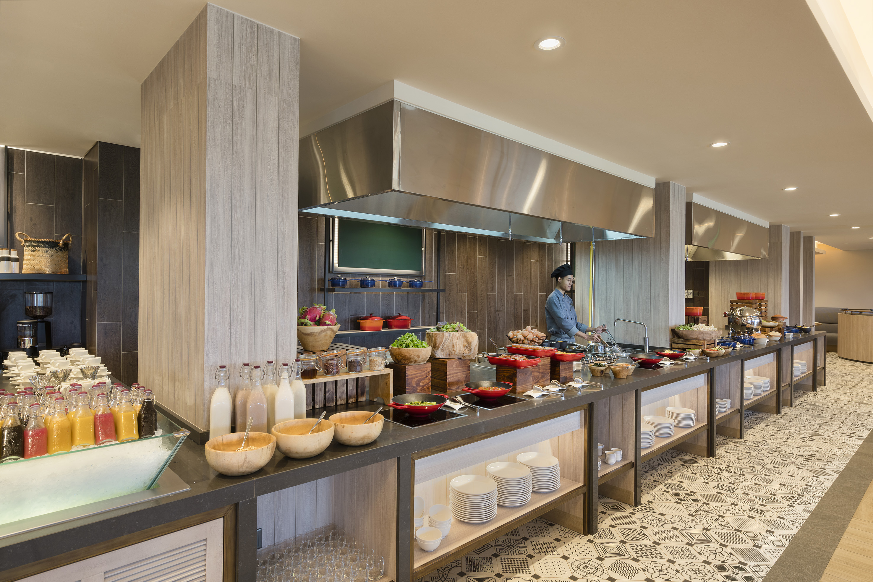 Chef at hotel breakfast buffet, live cooking station, fresh food, and juices.