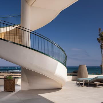 a spiral staircase with a deck chair and a palm tree