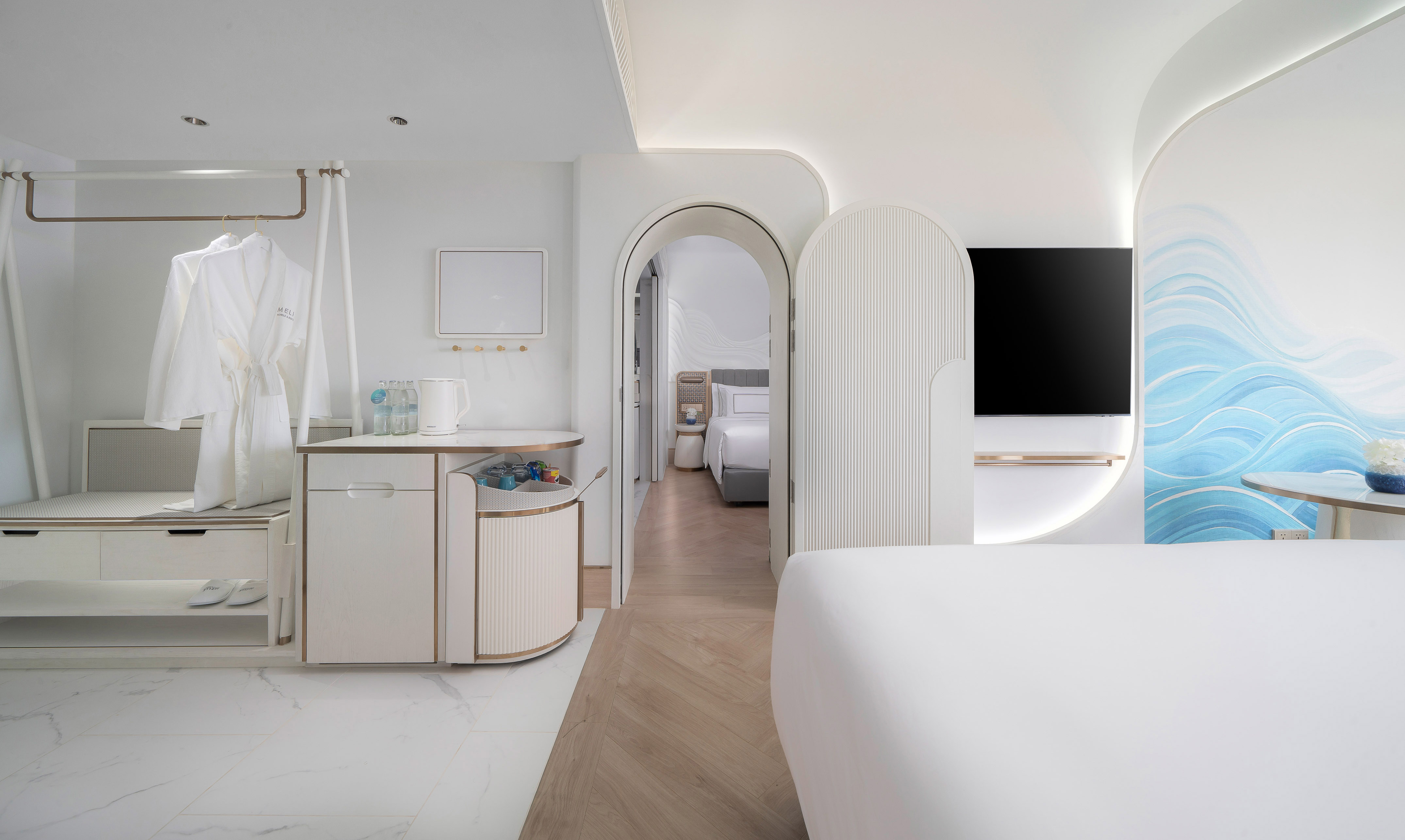 Modern hotel suite with white bathrobes, blue wave wall, minimalist decor.