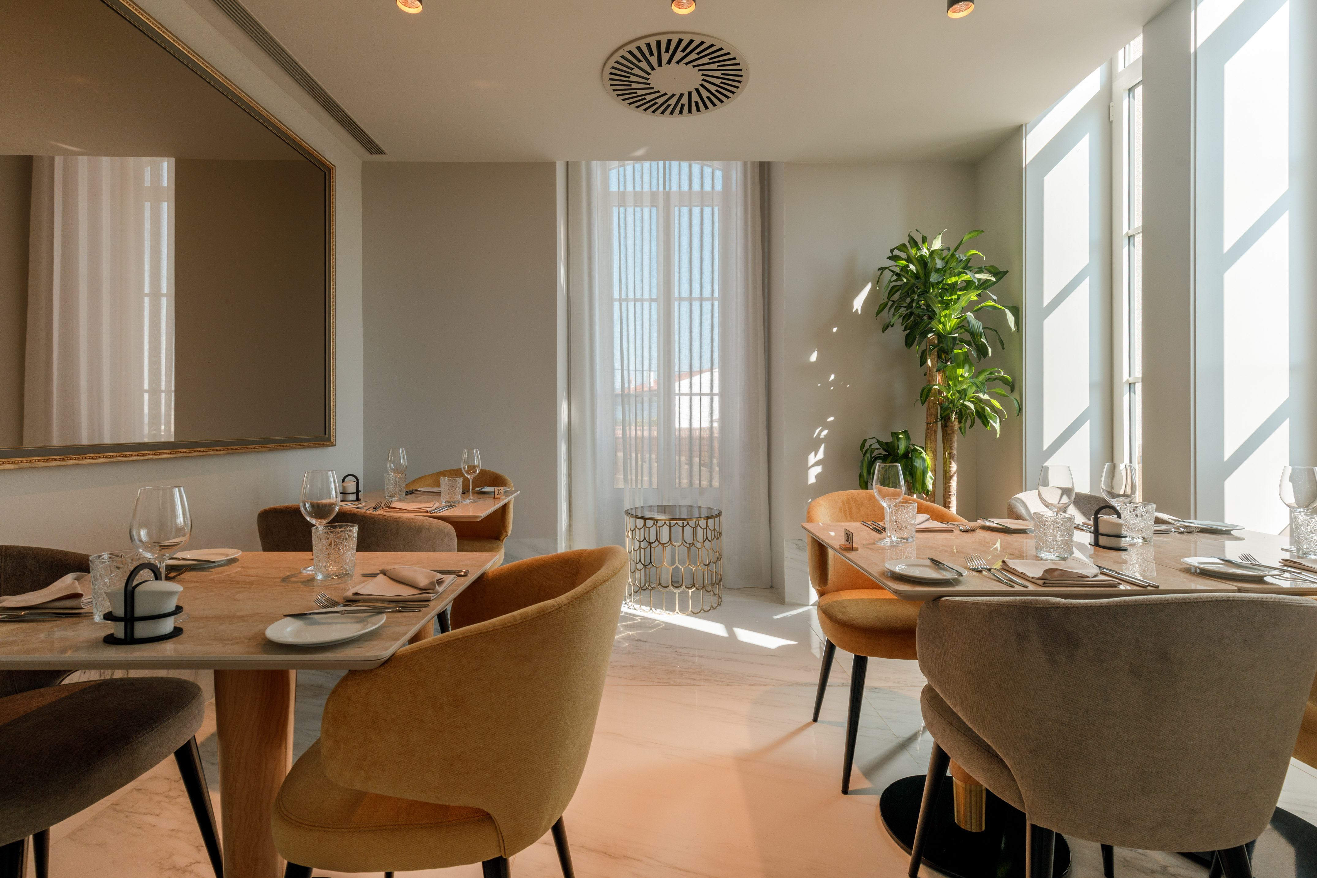 Modern restaurant interior with elegant dining tables and sunlit windows.