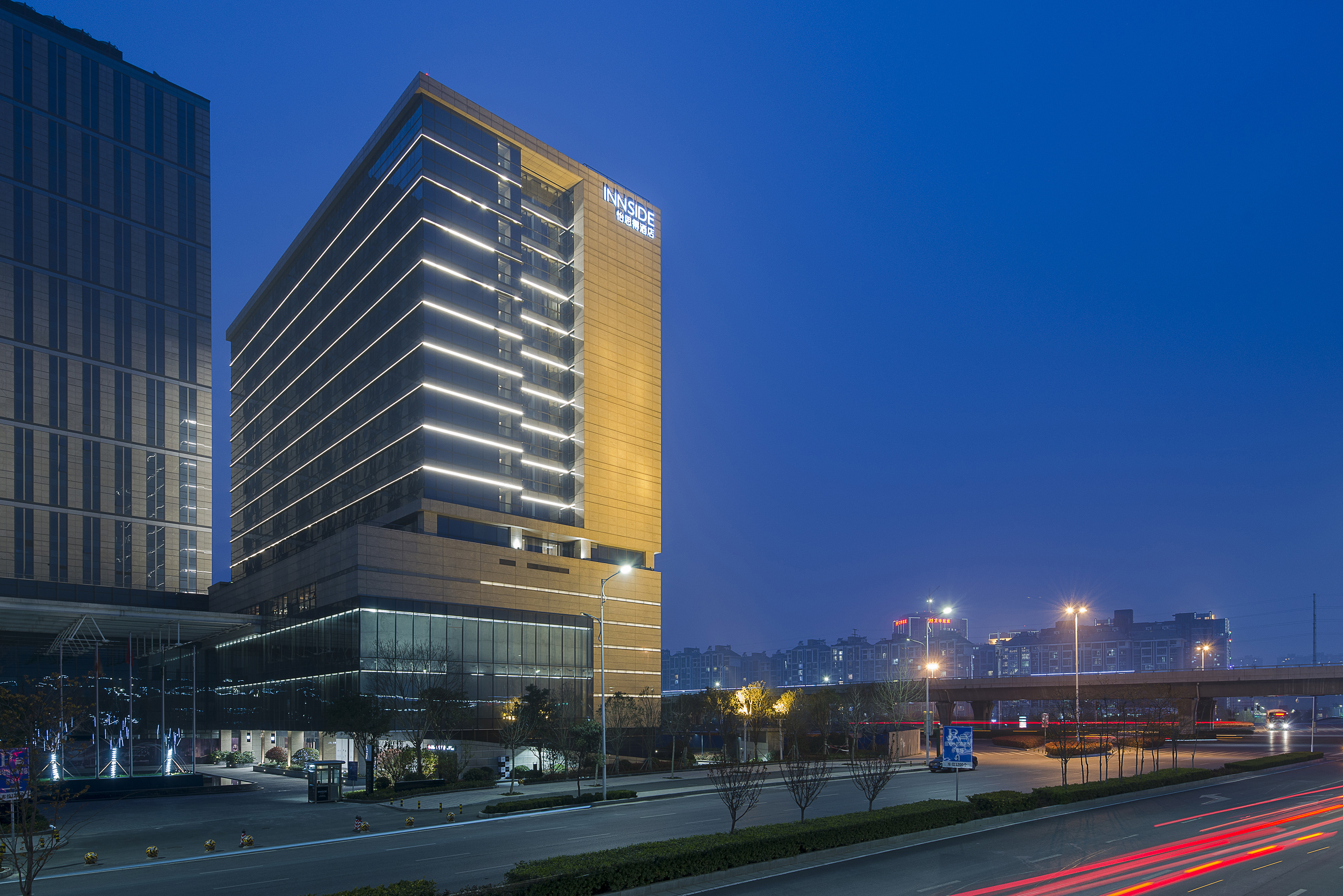 INNSIDE hotel modern building with illuminated facade, city road at night. - Innside I. Zhengzhou, Zhengzhou