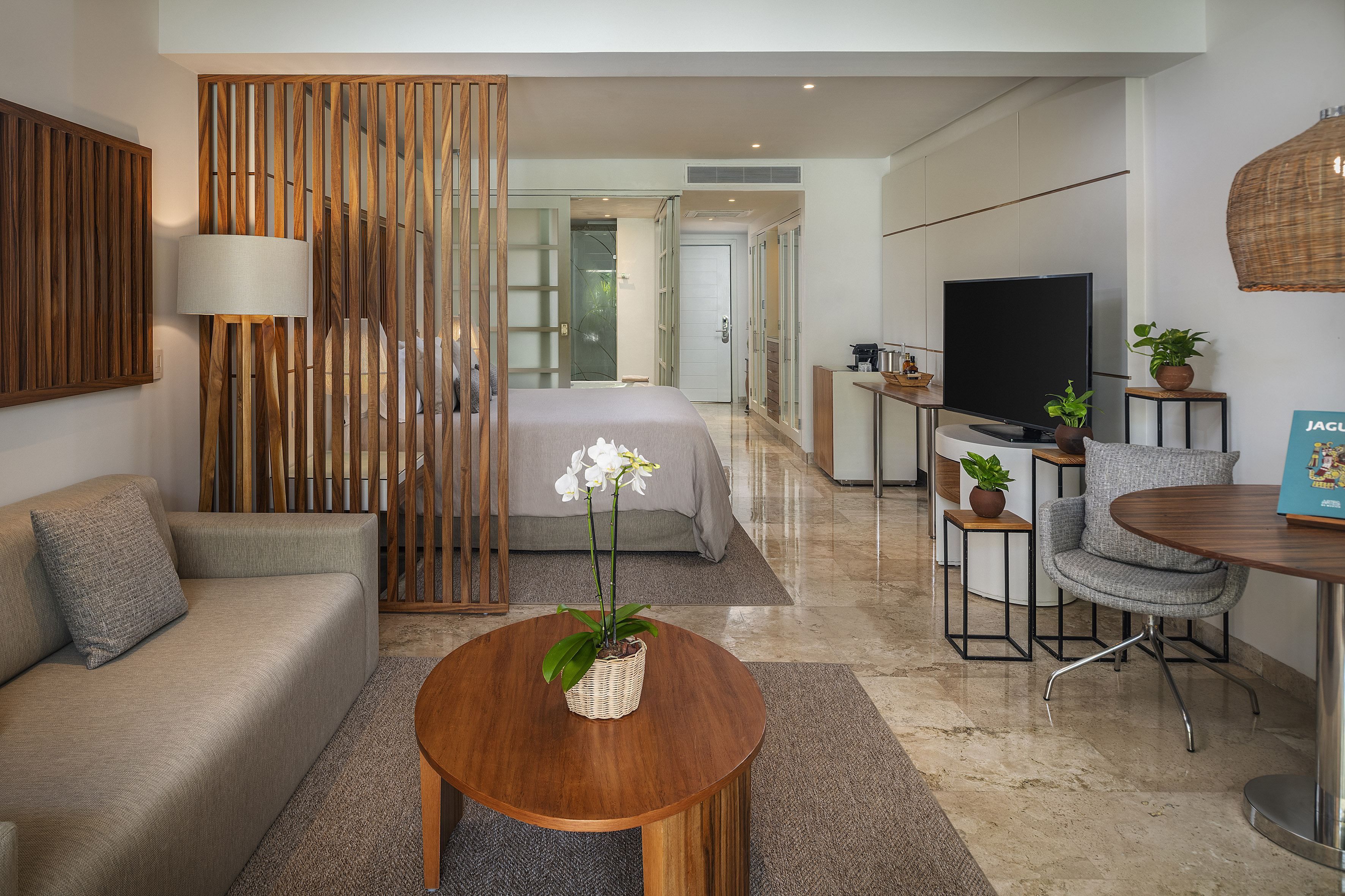 Modern hotel suite with living space, bedroom, wooden partition, marble floor.