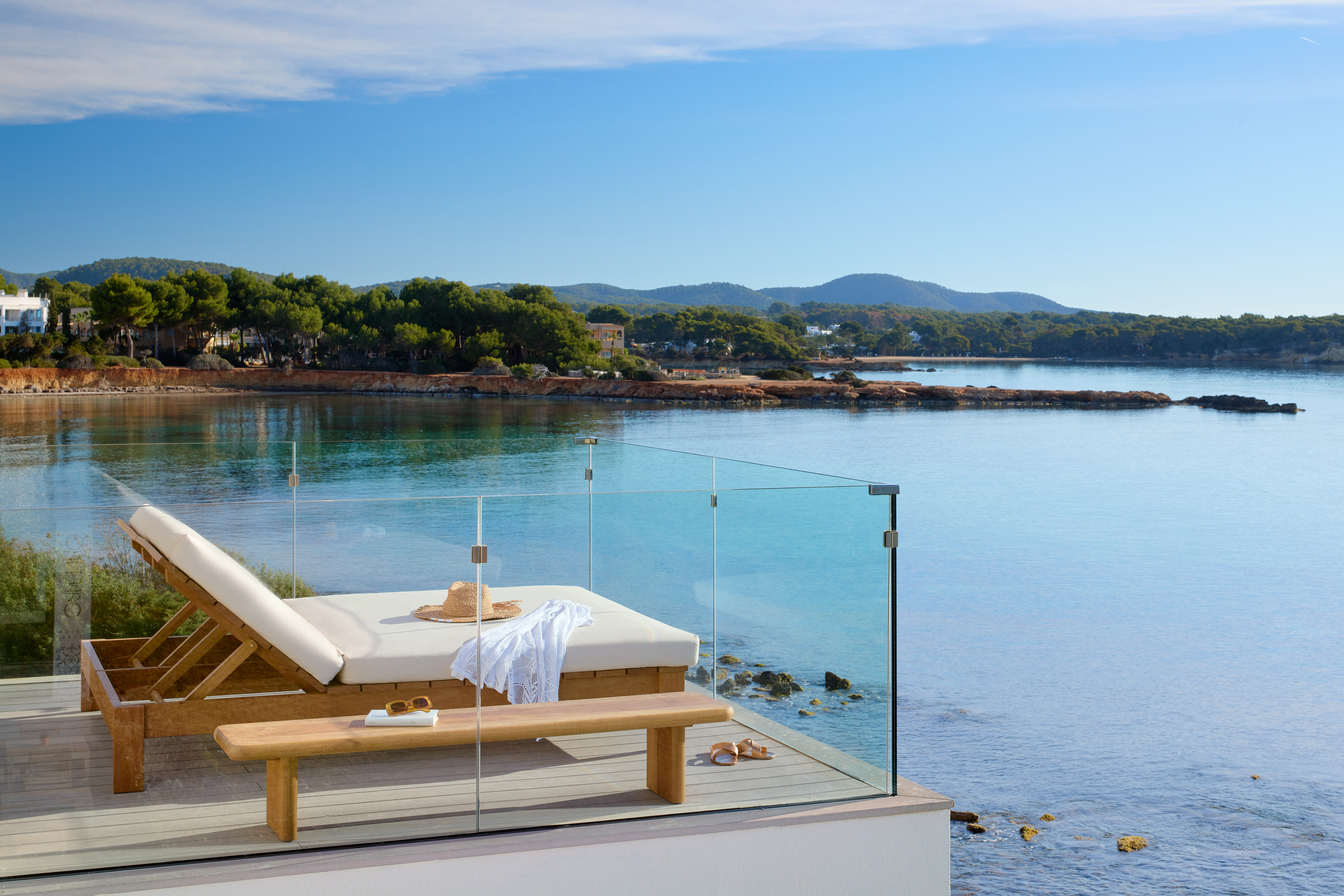 Coastal luxury terrace with sun lounger and calm sea views.