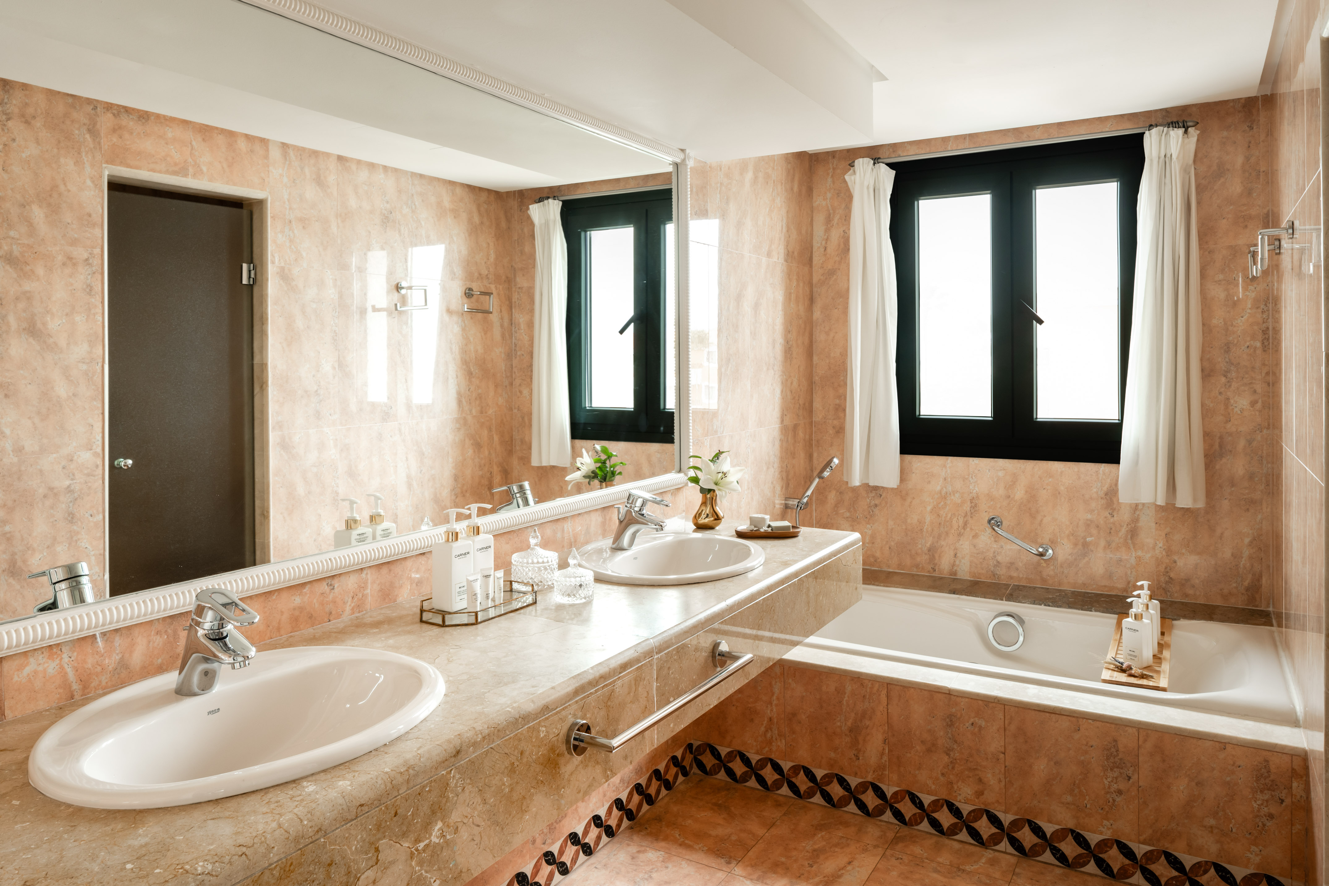 Modern marble bathroom with double vanity and bathtub.
