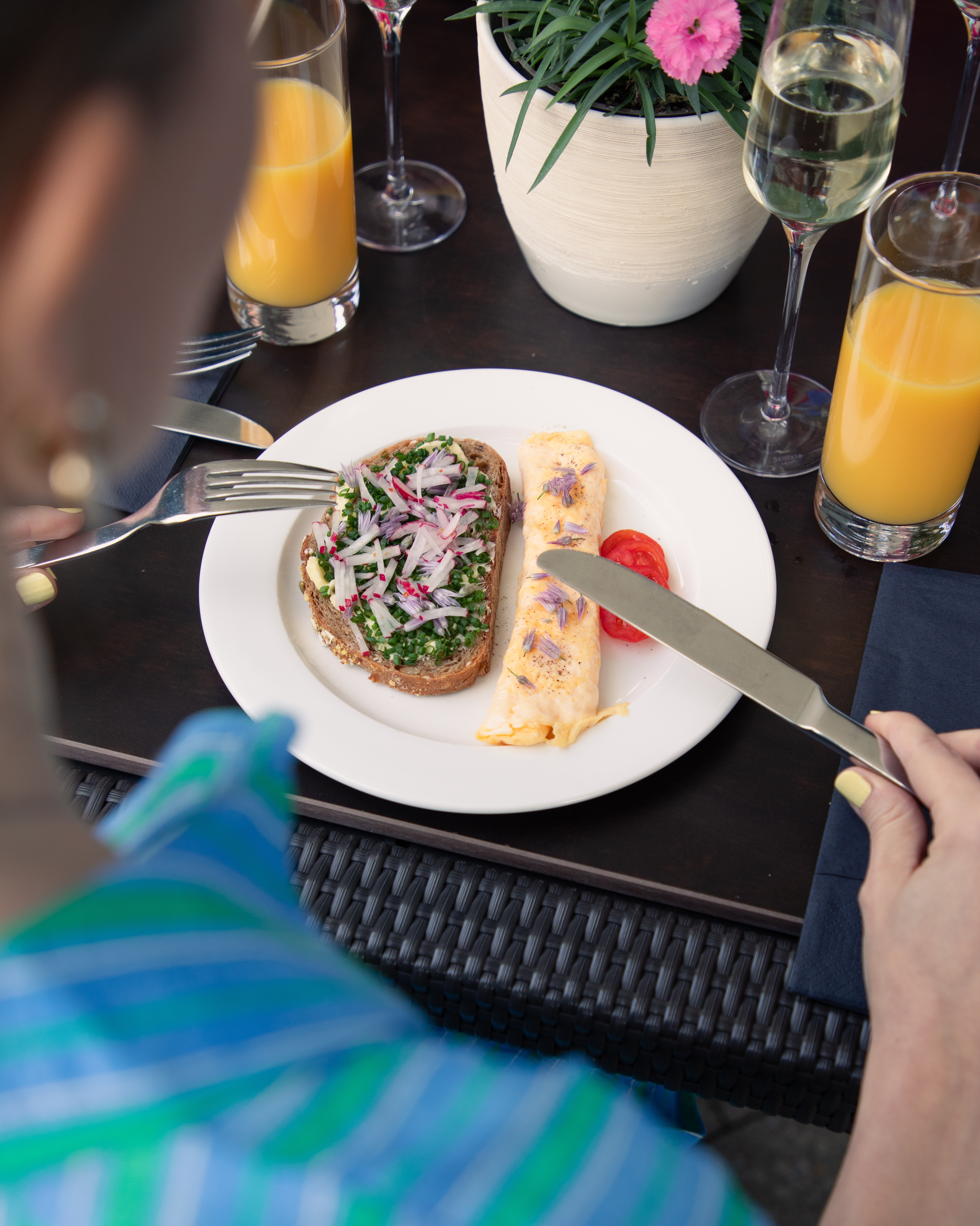 Outdoor brunch with bread, radish, chive omelet, orange juice, and champagne.