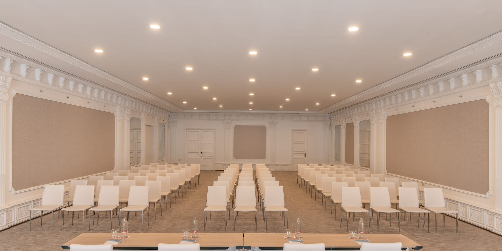 Elegant conference room with rows of white chairs and a front presentation table.