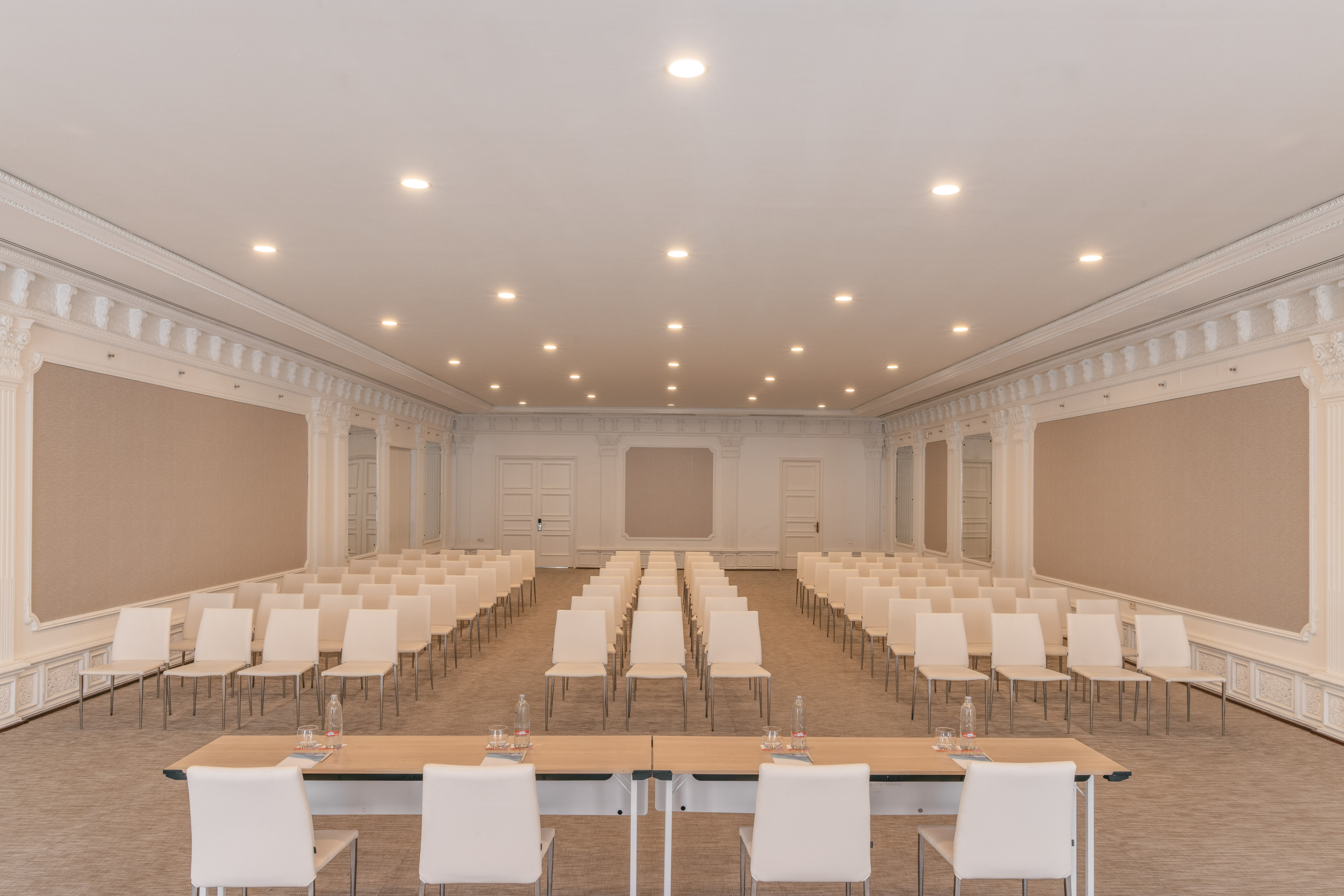 Elegant conference room with rows of white chairs and a front presentation table.