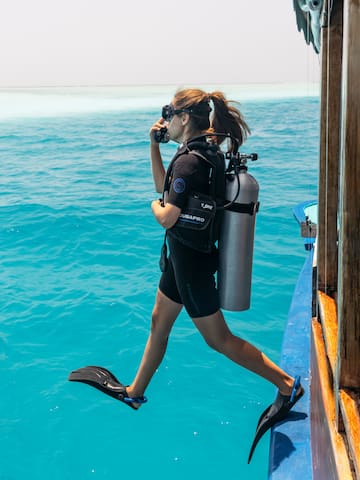 a woman in scuba gear and flippers walking on a boat