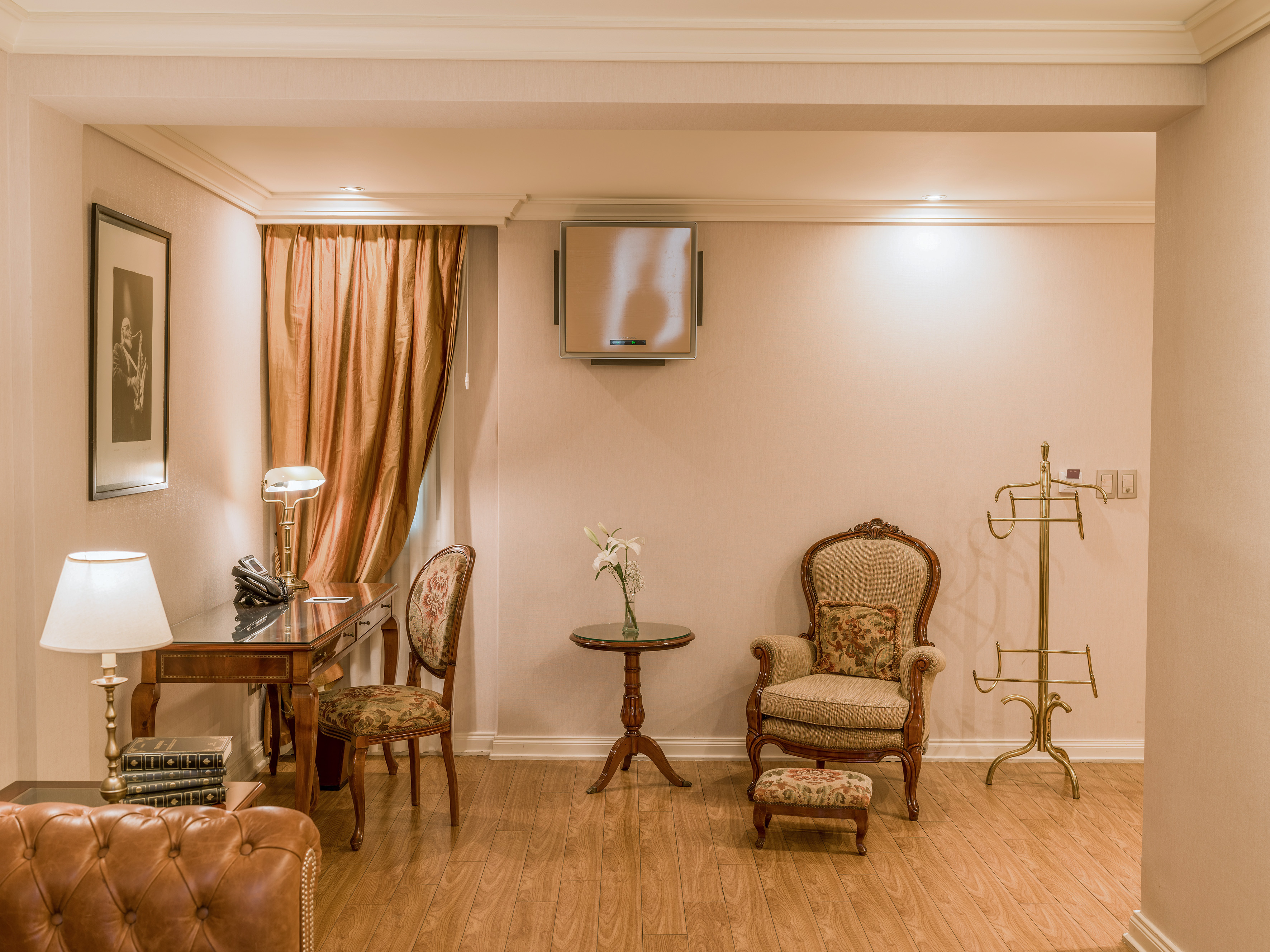 Luxurious hotel suite with vintage furniture, work desk, seating area.