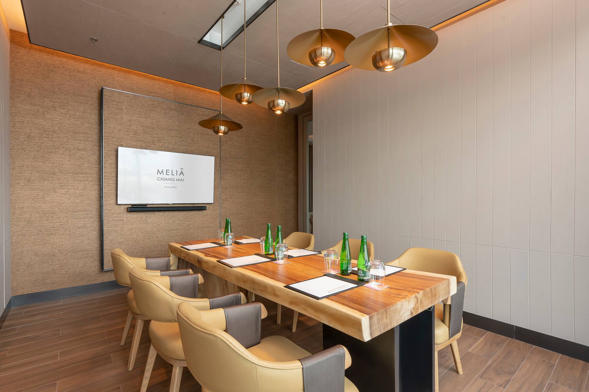 Meliá Chiang Mai meeting room with modern wood table, tan chairs, and screen.