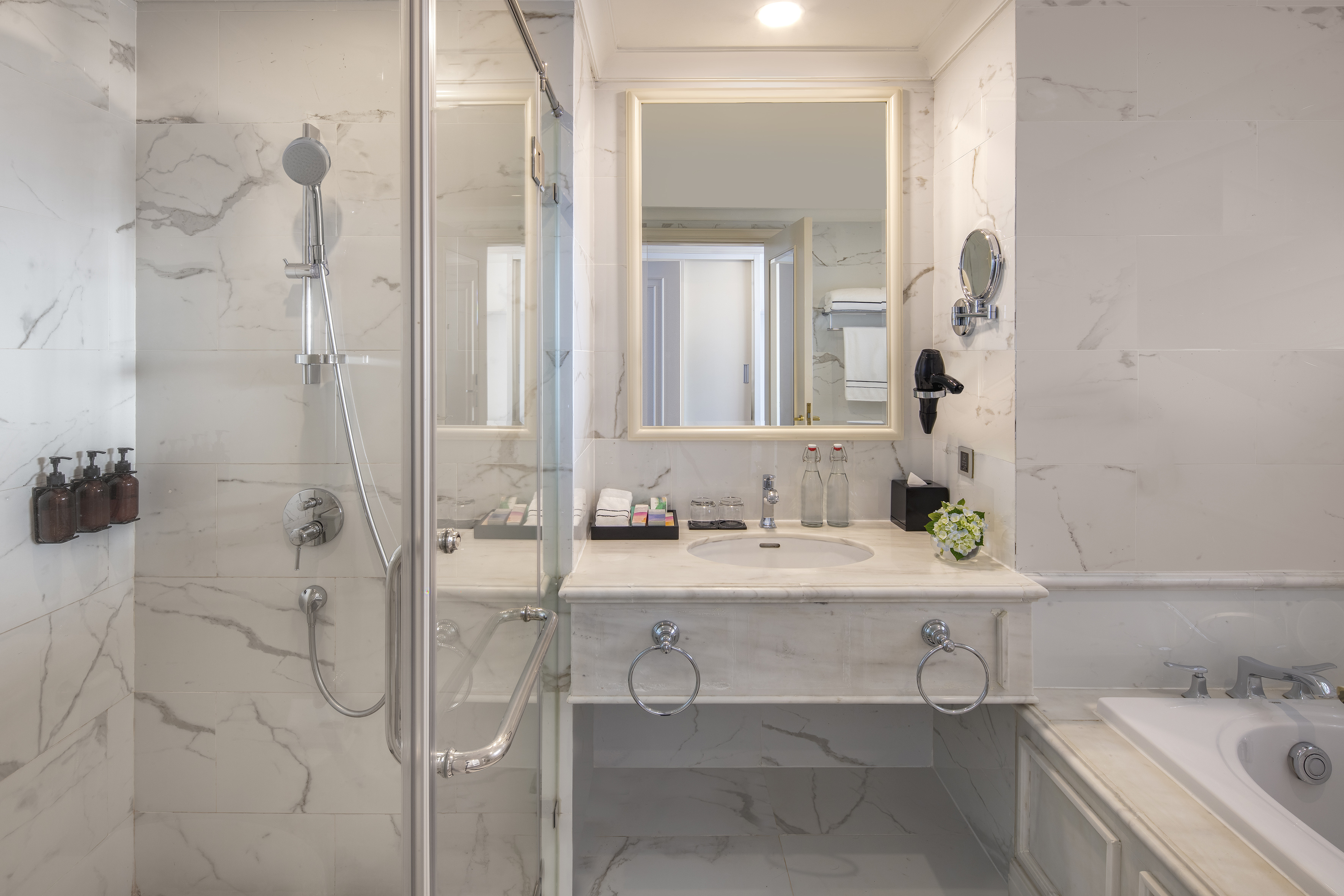 Luxury marble bathroom with shower, vanity, mirror, and bathtub.